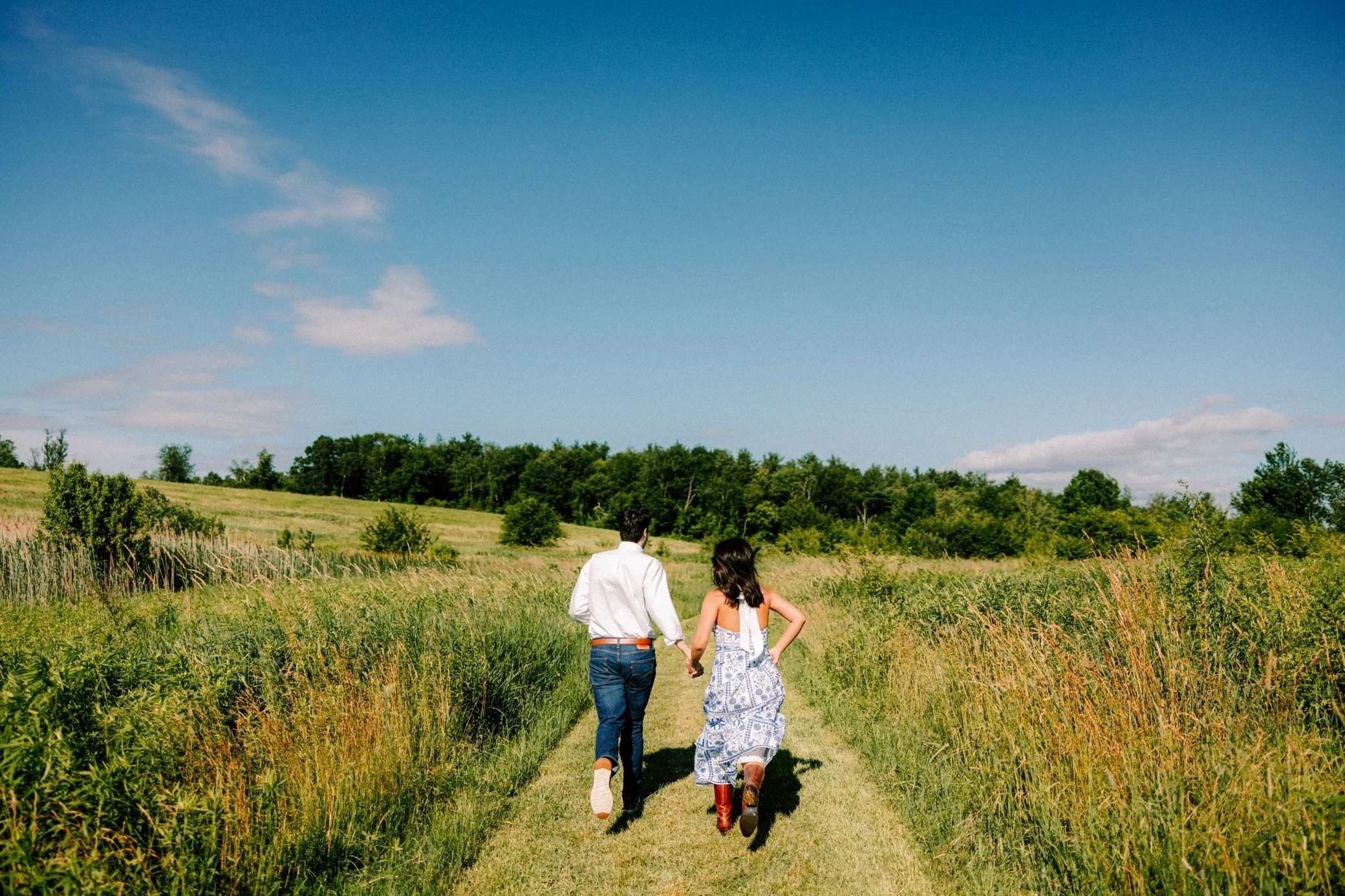  engaged couple run through summer field at ooms conservancy 