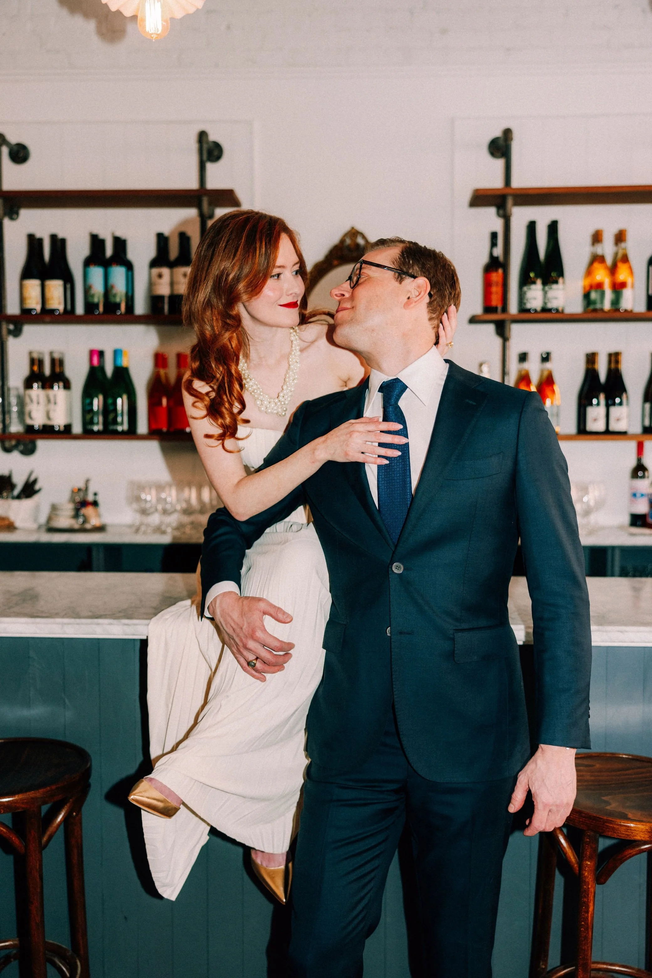  old hollywood glam couple sit on bar at brunette in Kingston, NY during their engagement photography shoot 