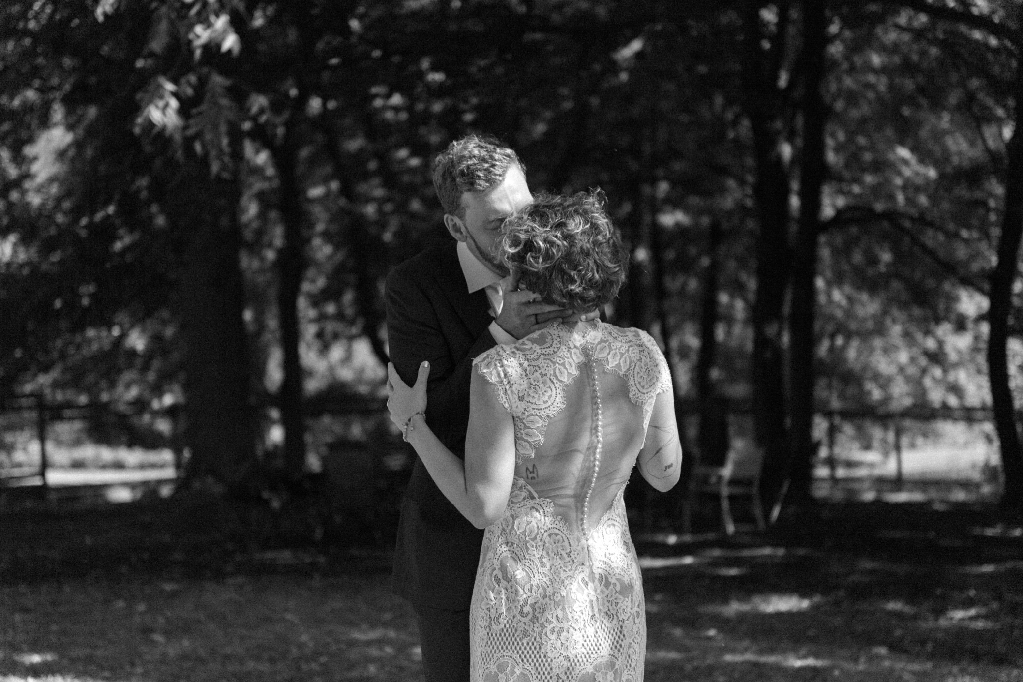  black and white photo of groom holding brides face and kissing her  