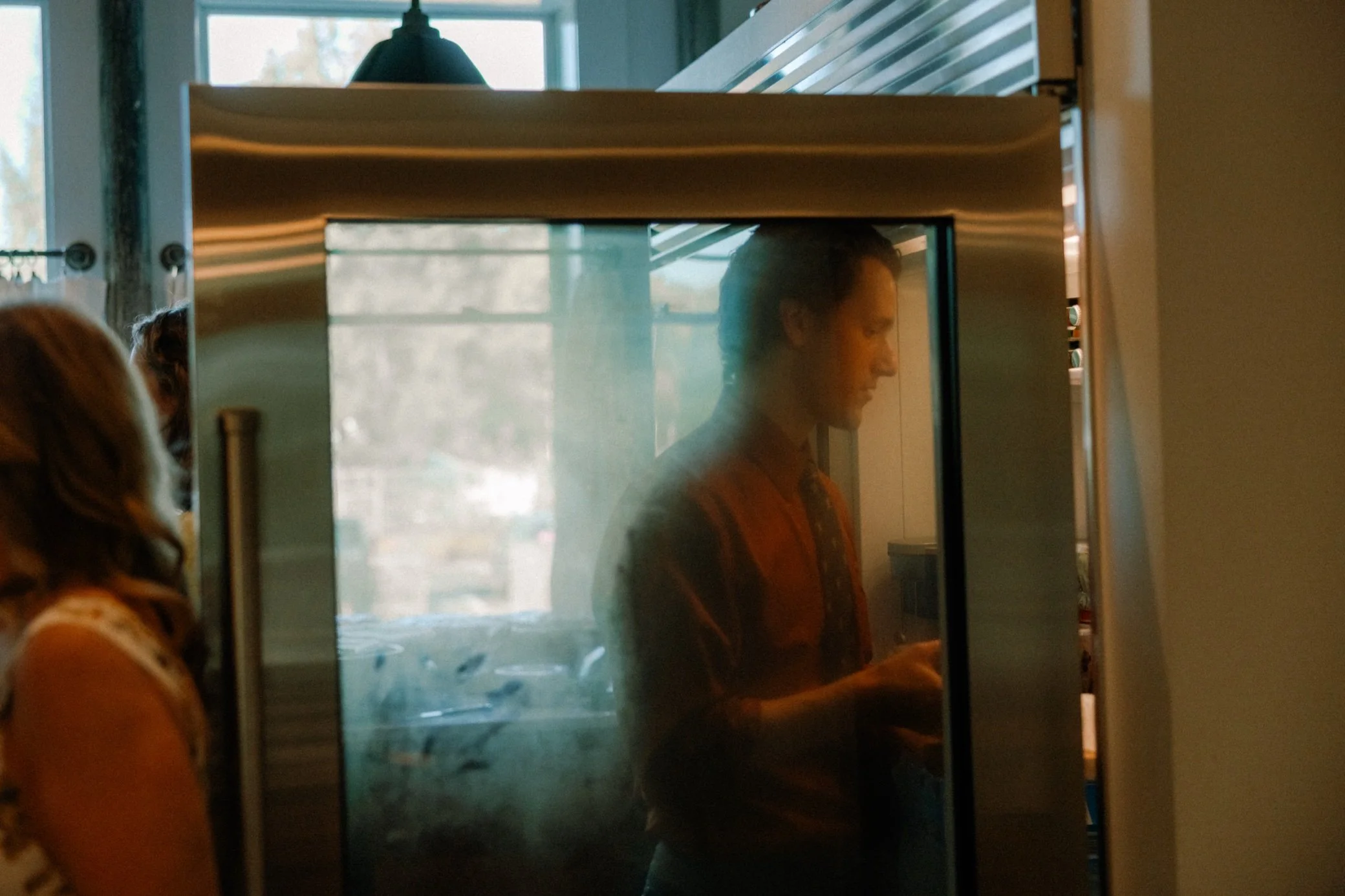  wedding guest stands in the fridge light of the mansion kitchen at the yard in beacon, ny 