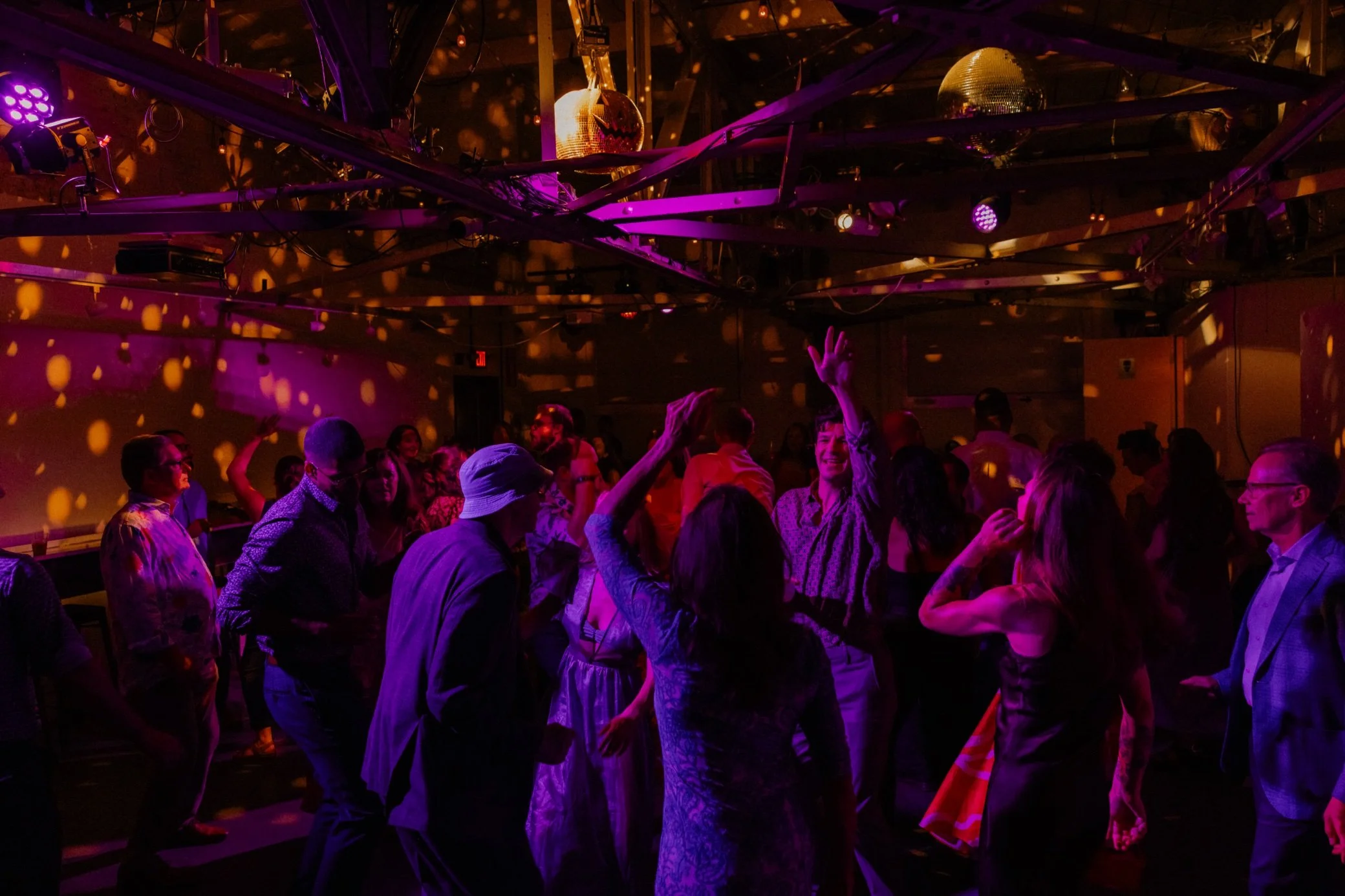  Dramatic purple lighting and people dancing to vinyl DJ dance set at LNJ’s The Yard wedding venue in beacon, ny 