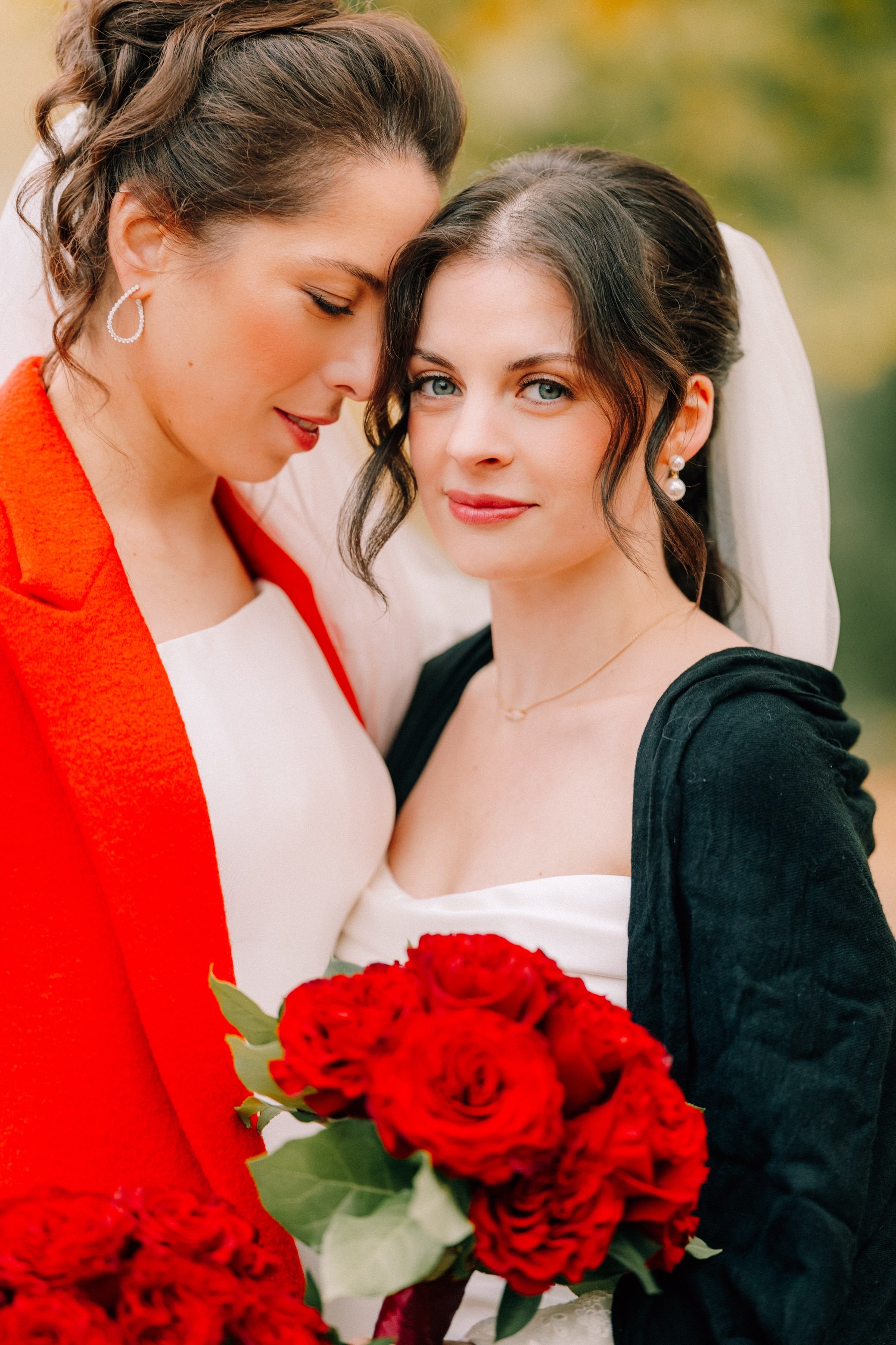  brides embracing with red shawl and red bouquet at the roundhouse 
