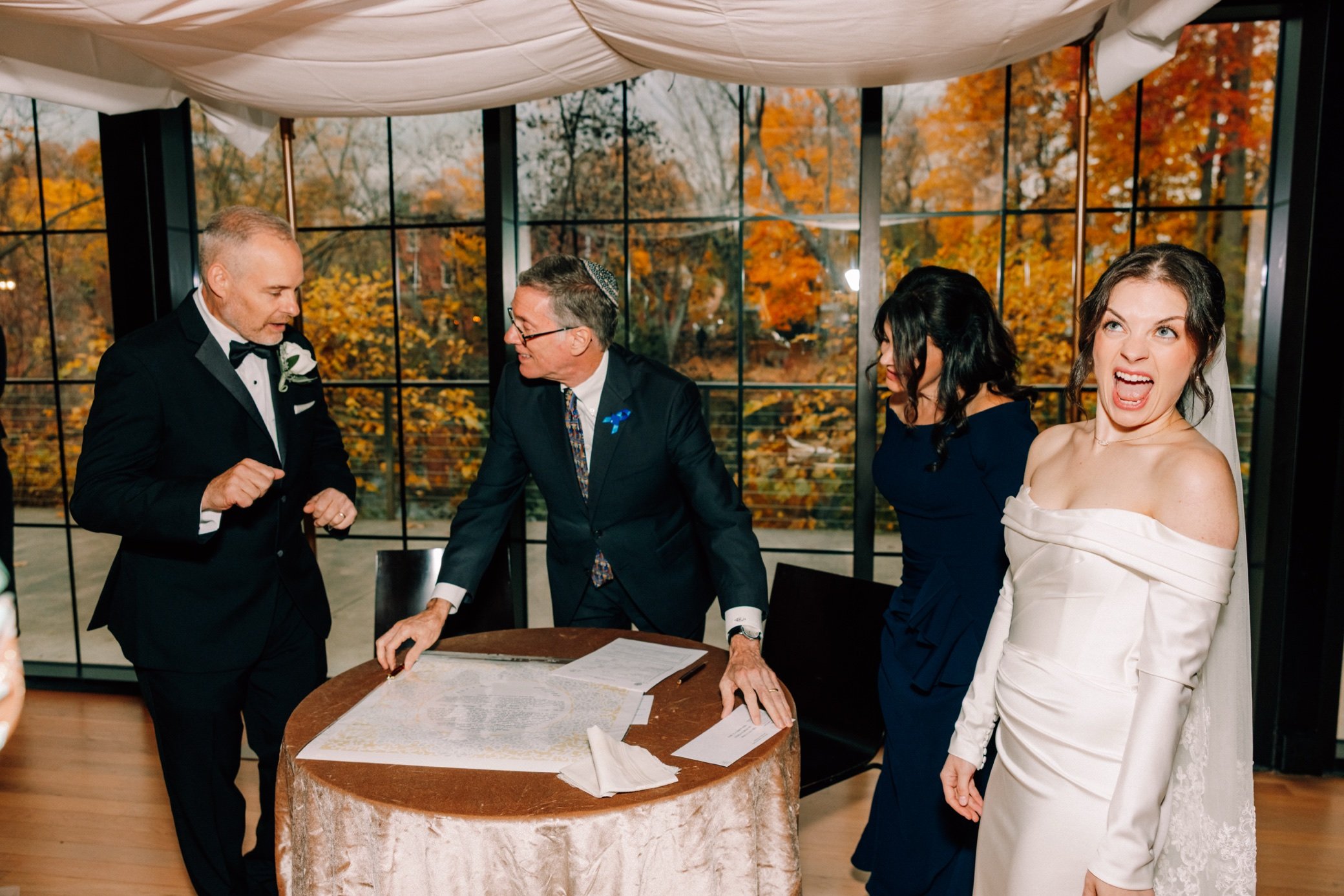  bride excited about ketubah signing while dad talks to rabbi at the roundhouse 