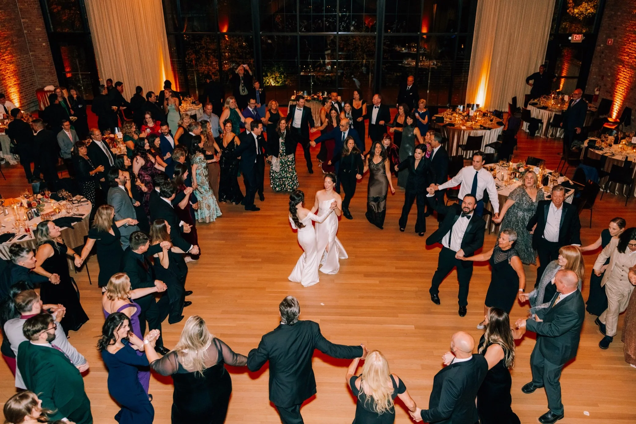  brides in the center of the dance floor surrounded by guests during the hora at the roundhouse 