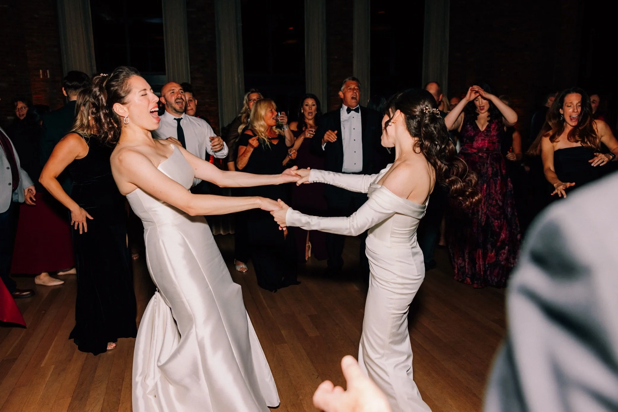  brides hold hands and spin surrounded by guests at the roundhouse  