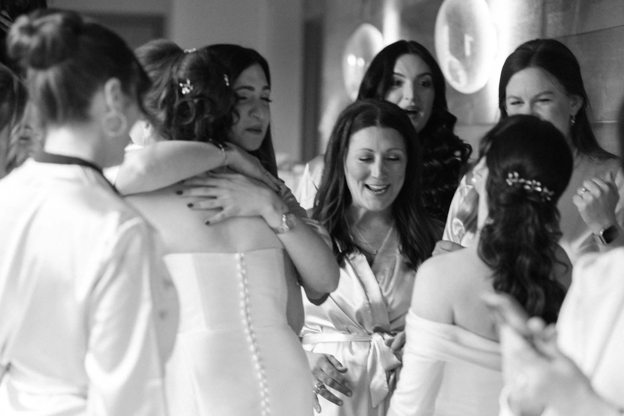  brides and friends hug during their first look at the roundhouse 
