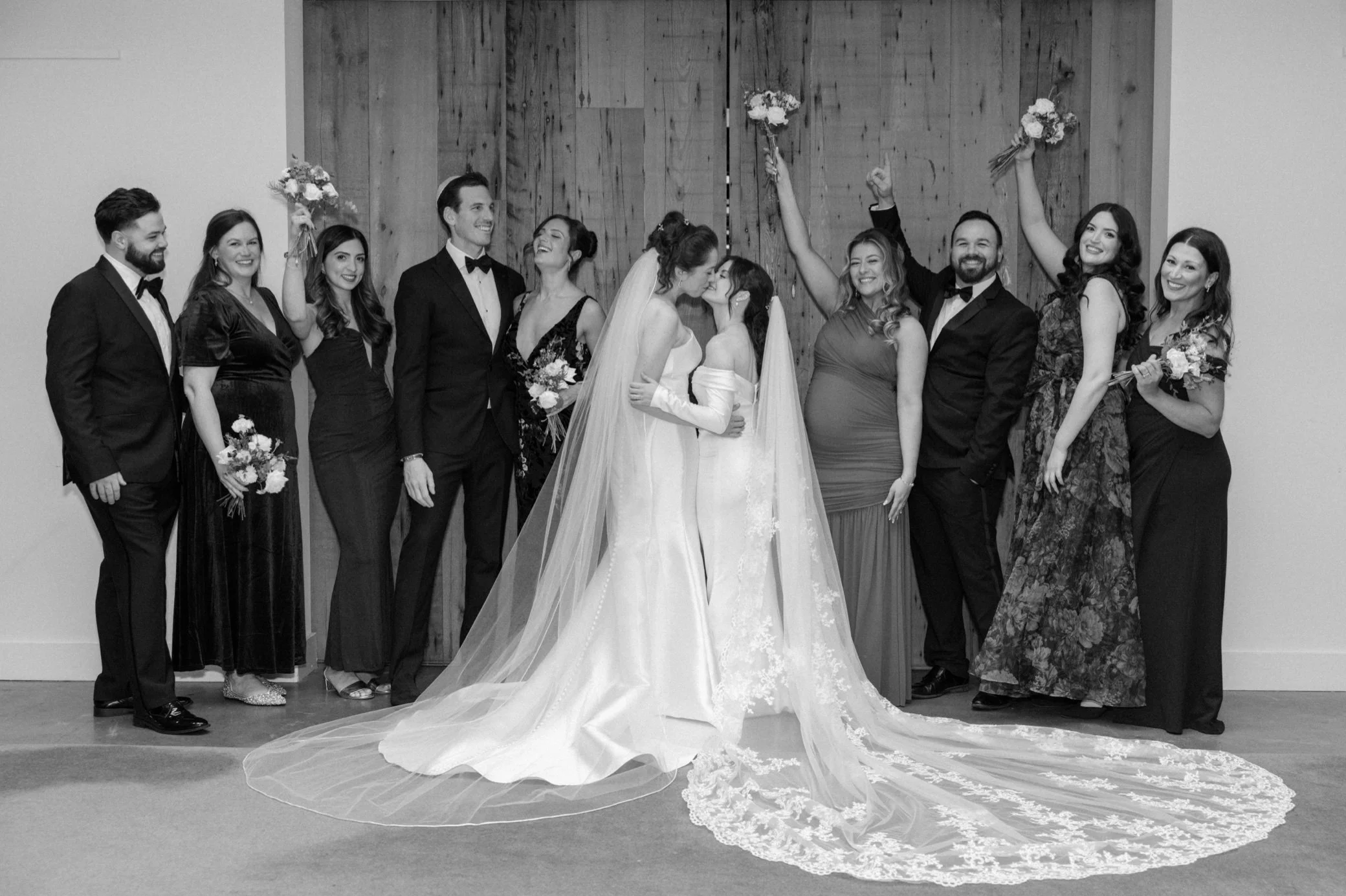  brides kiss while wedding party cheers at the roundhouse 