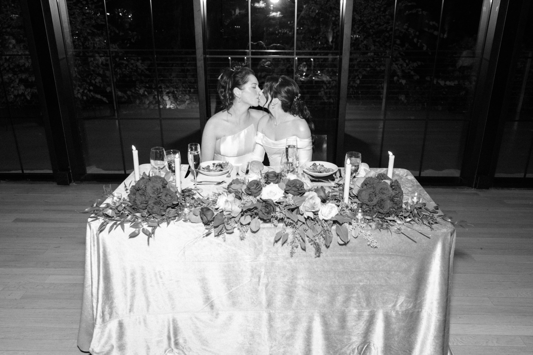  brides kiss at their sweetheart table at the roundhouse 