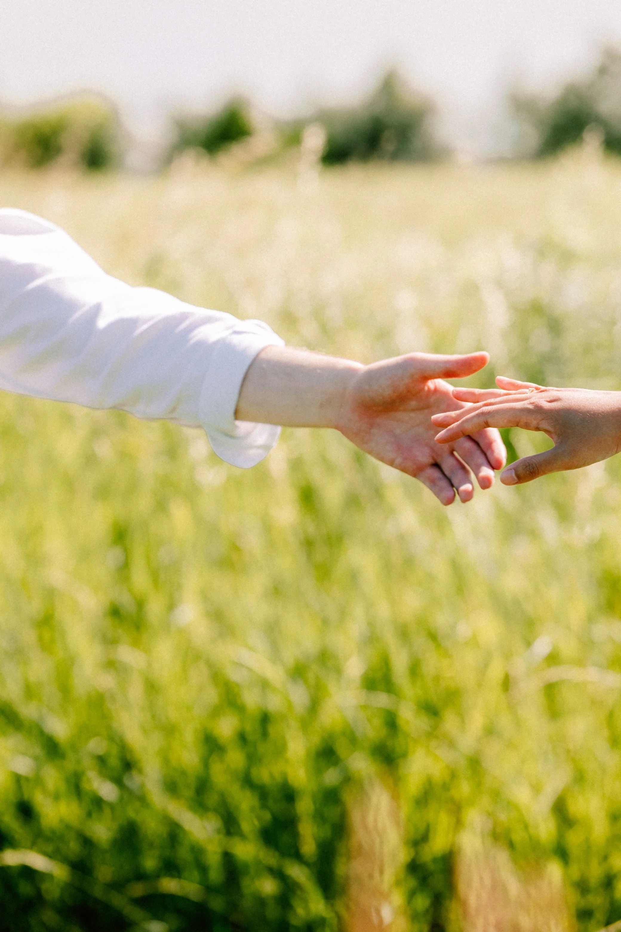 couple reaching for each others hands during engagement shoot