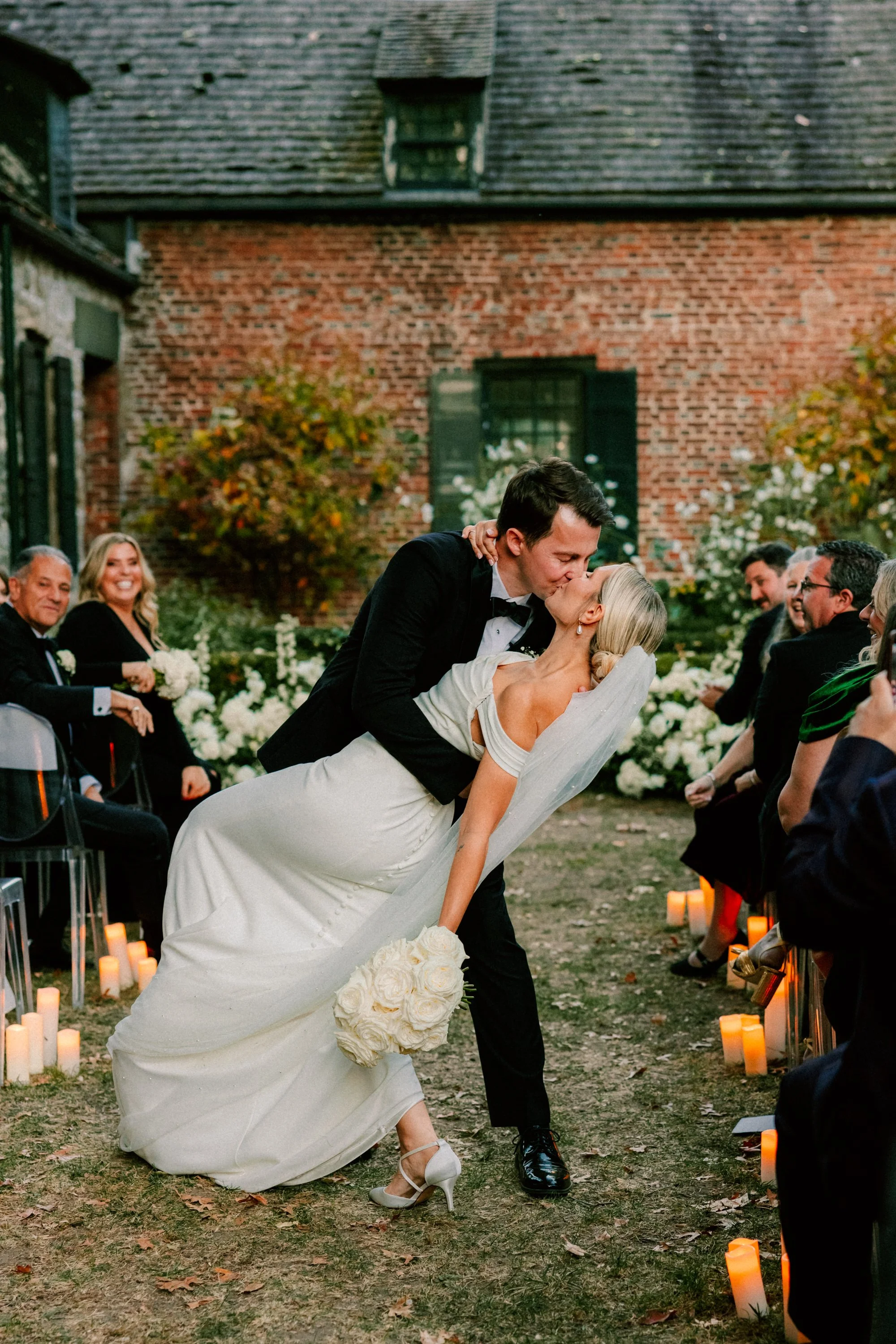 couple kiss in the aisle surrounded by pillar candles on their wedding day at Senate Garage in Kingston, NY