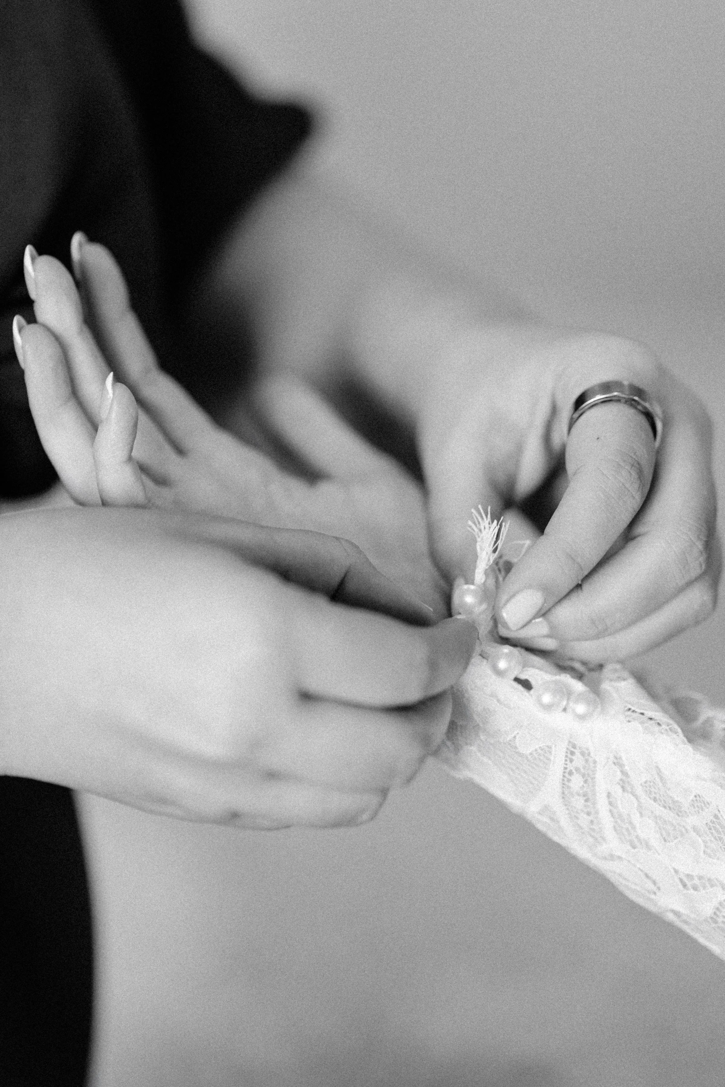 black and white photograph of bride's sleeve being buttoned up during her getting ready on her wedding day at the ashford estate
