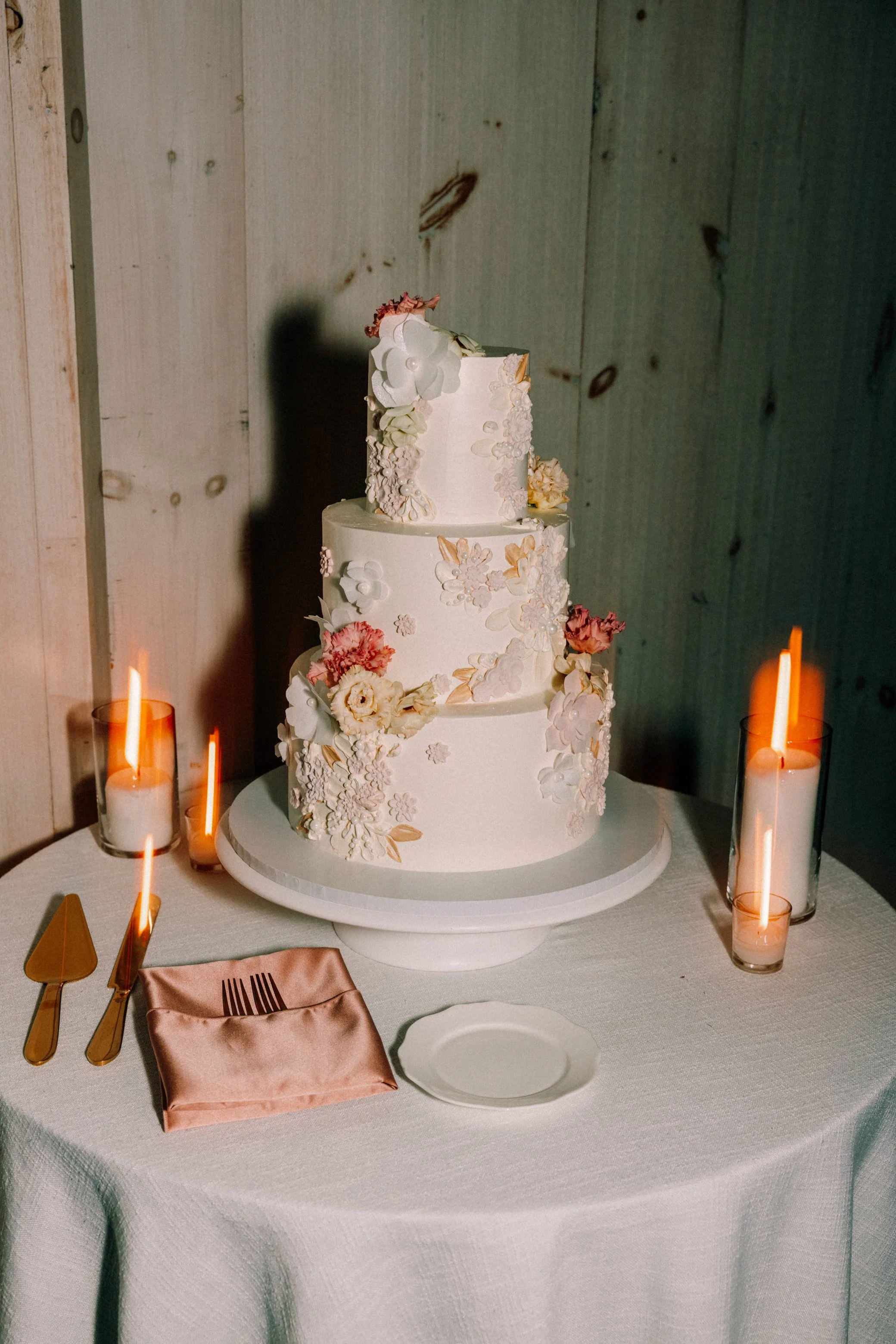 photograph of wedding cake with delicate flowers and candles at glenmere mansion