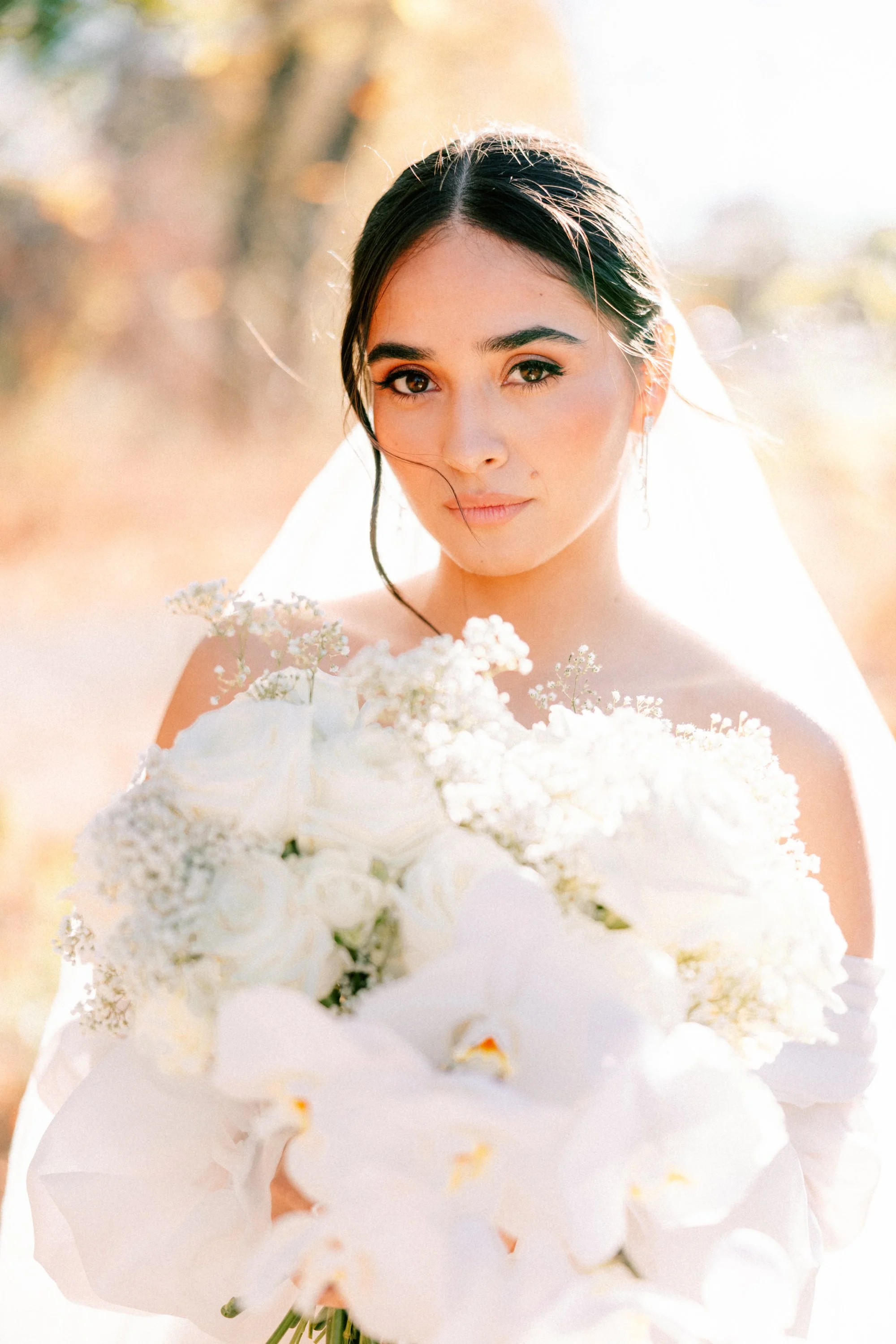 bride looking into the camera while holding a large white bouquet on her wedding day at the roundhouse