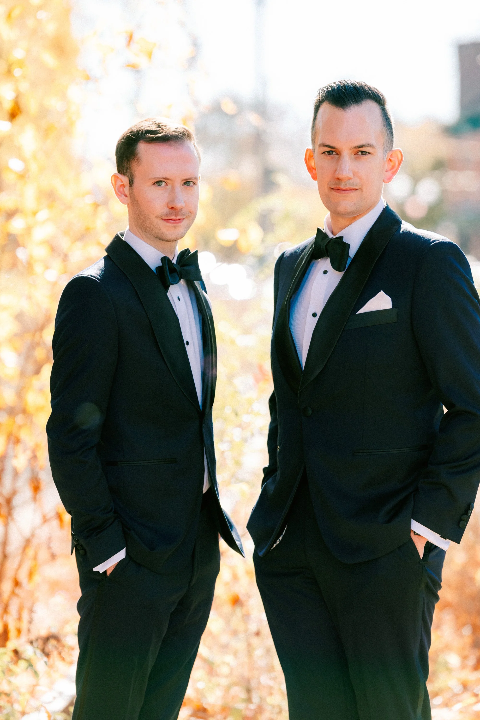 wedding couple standing next to each other while wearing tuxedos at the roundhouse