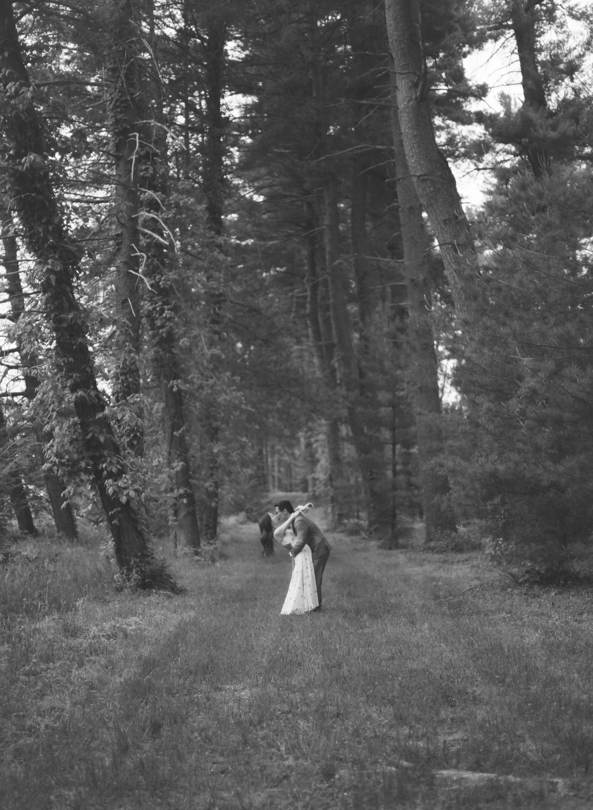 couple kissing in the woods during their engagement photography session at vanderbilt mansion