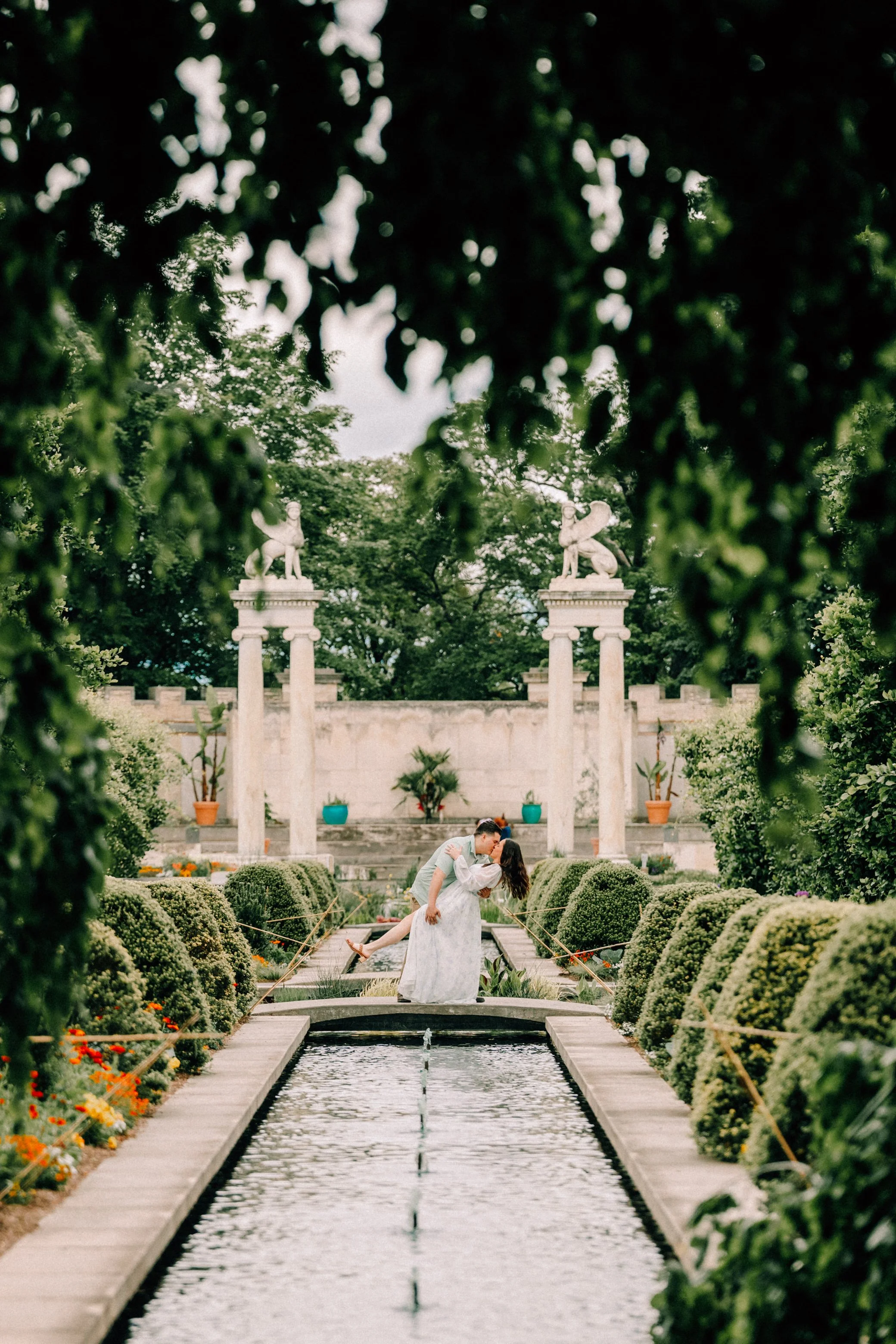 couple dip and kiss during their engagement shoot at Untermyer gardens