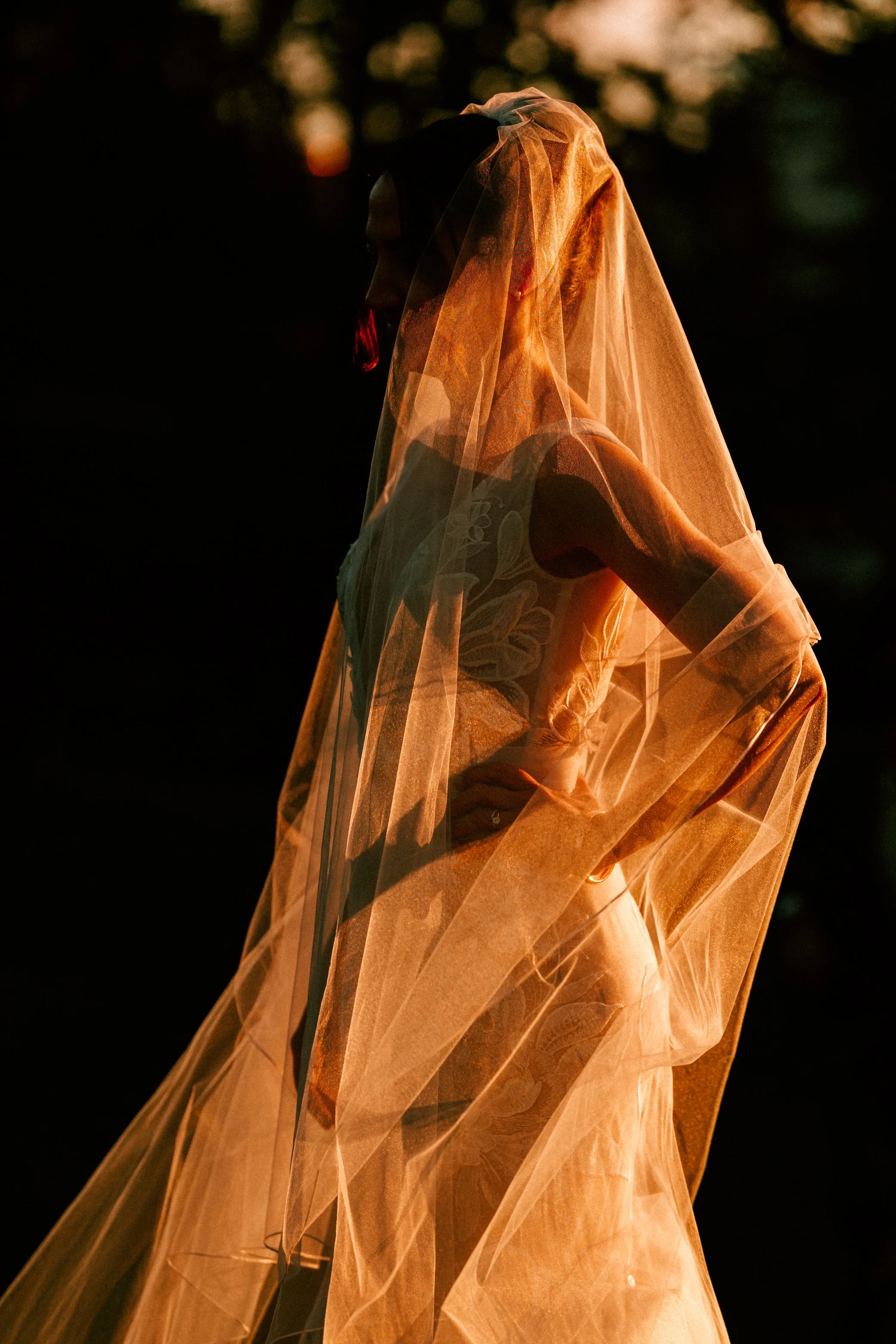 bride stands in the golden hour sun while it illuminates her veil on her wedding day at the roundhouse