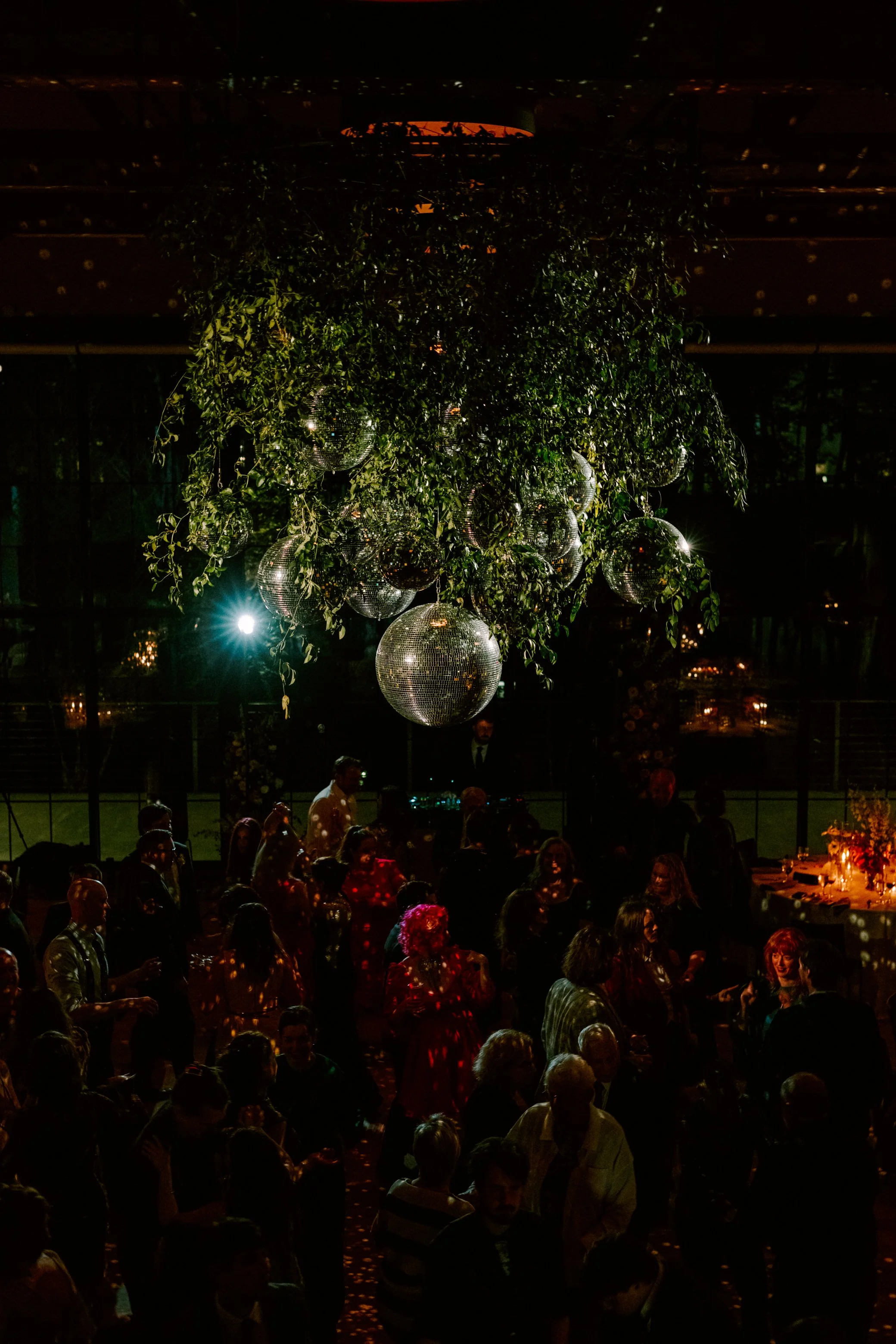 wedding guests dancing under the disco ball and floral installation hanging from the reception room rafters at the roundhouse