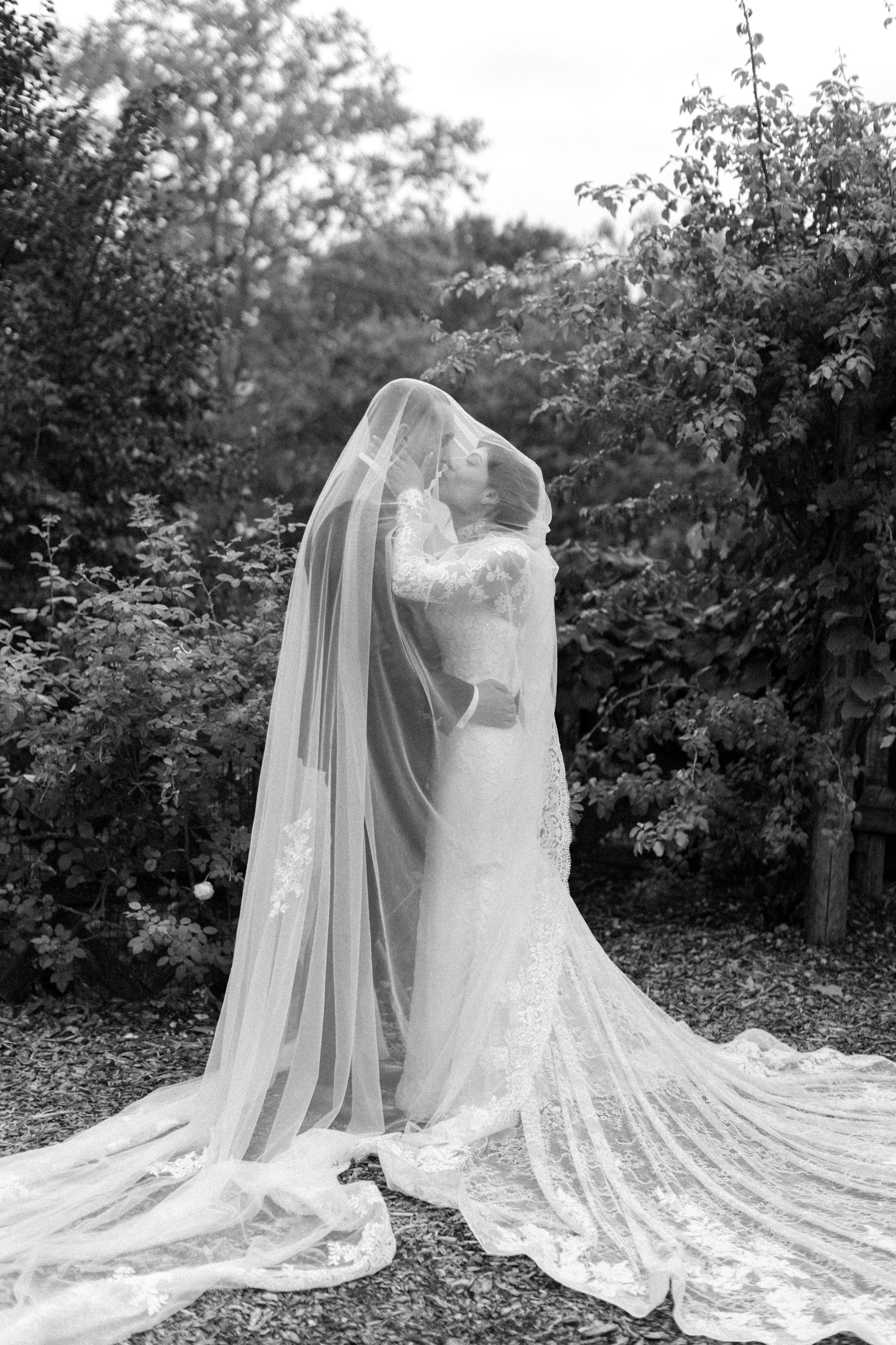couple embracing under wedding veil during their hudson valley elopement at untermyer gardens