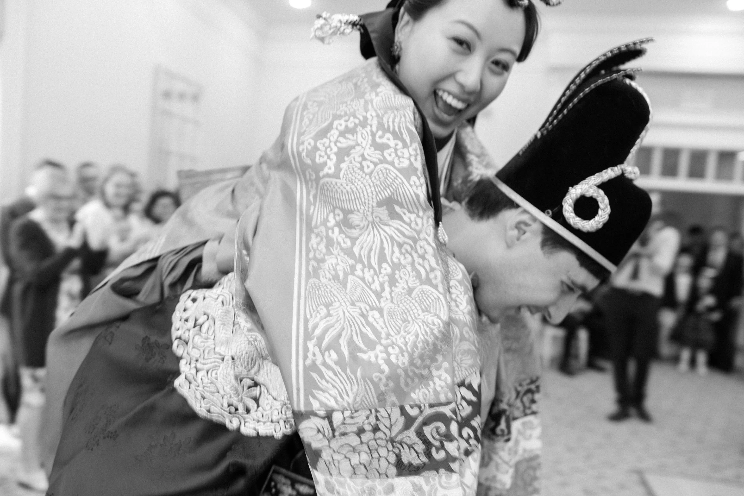 groom gives bride piggy back ride while they laugh during their paebaek wedding ceremony in otesaga hotel
