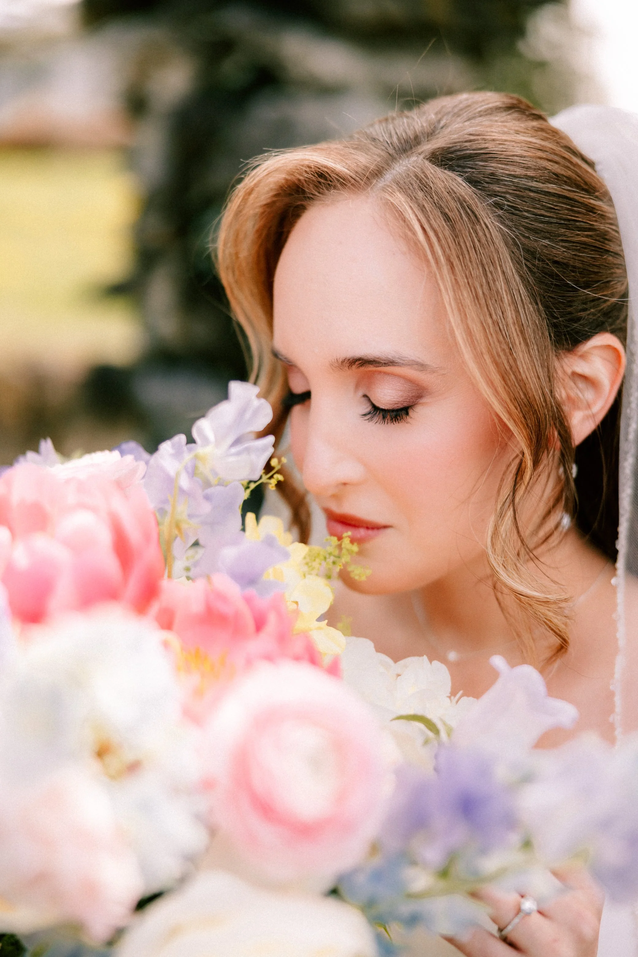 portrait of left side of brides face with her eyes closed and holding her wedding bouquet close to her face in garrison ny