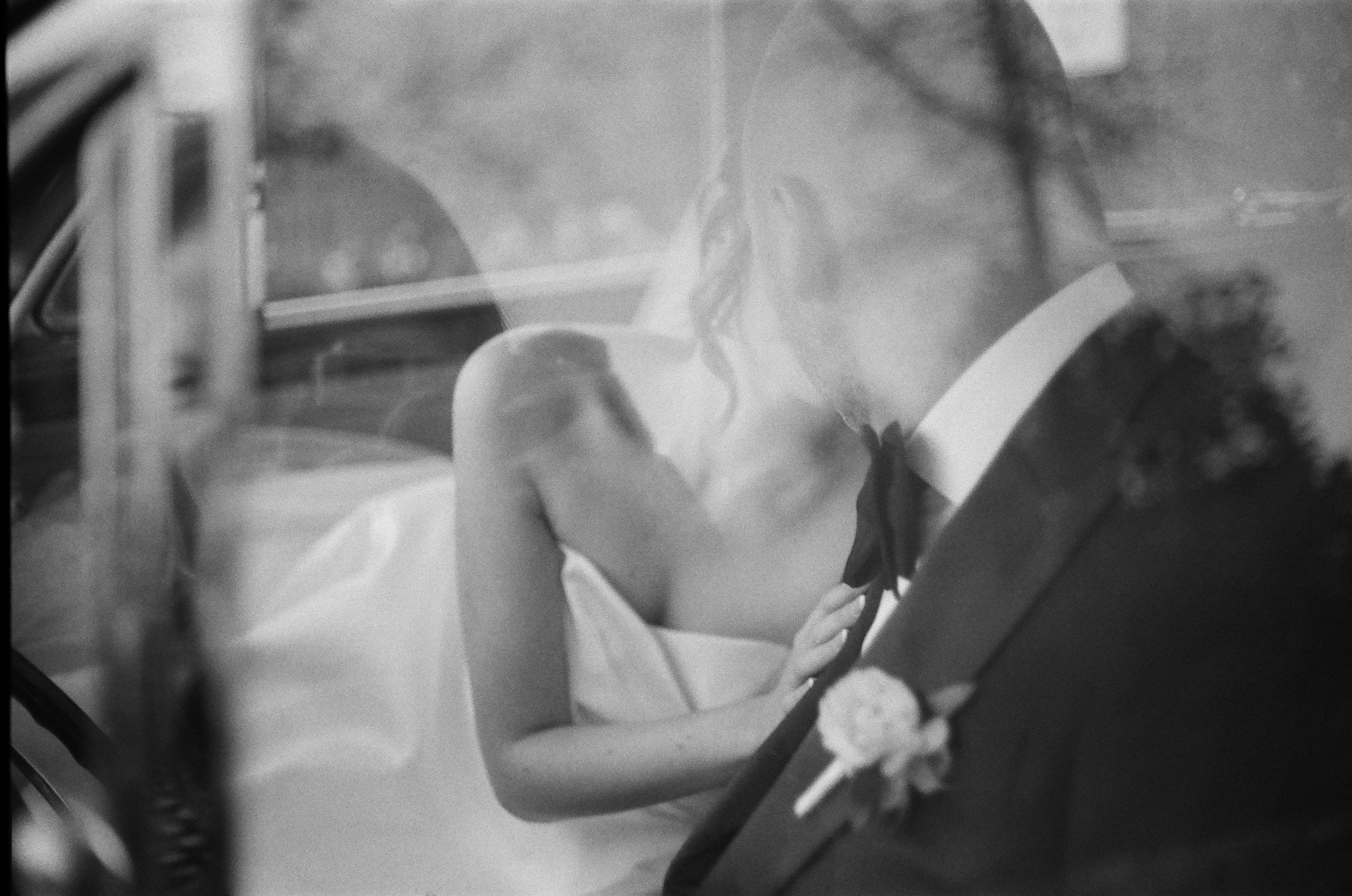 medium format film photograph of bride and groom kissing inside a vintage classic car in garrison new york