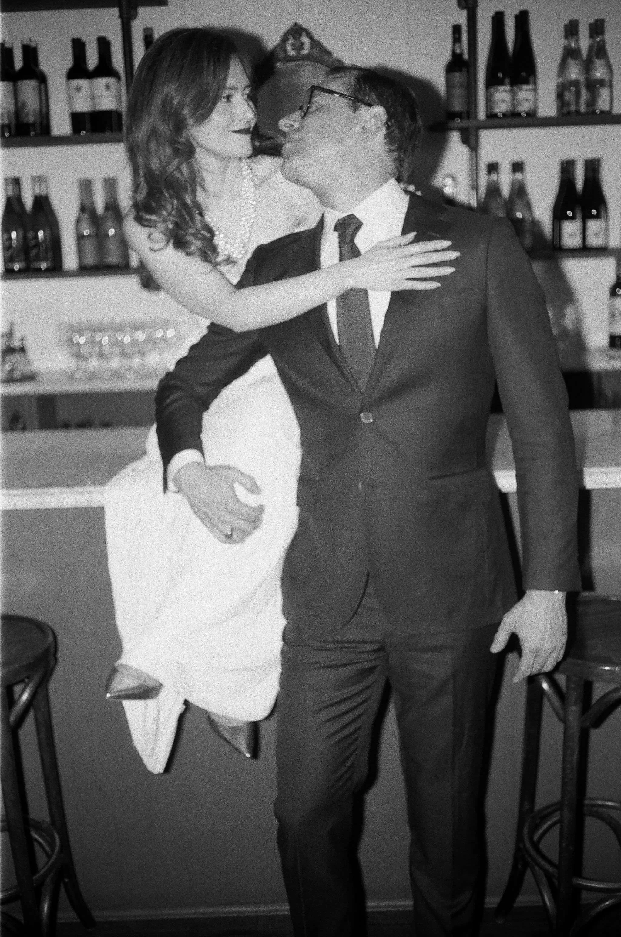 woman sitting on bar with man looking at her during their engagement photography shoot at brunette wine bar in kingston new york