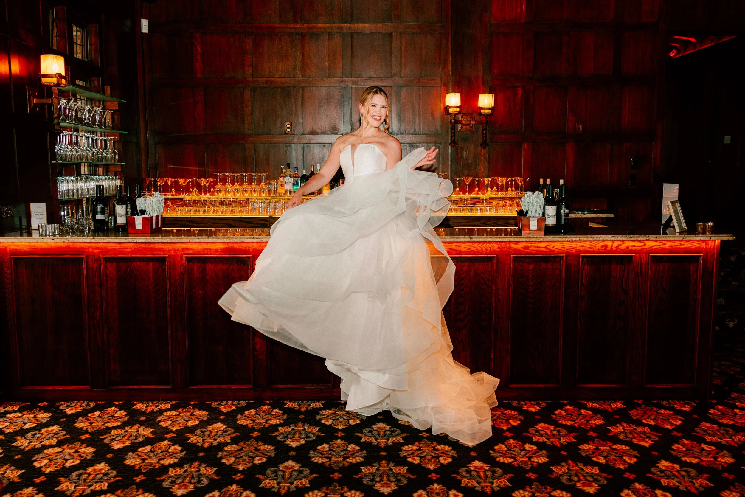 bride throwing her dress while sitting on bar on her wedding day at le Chateau