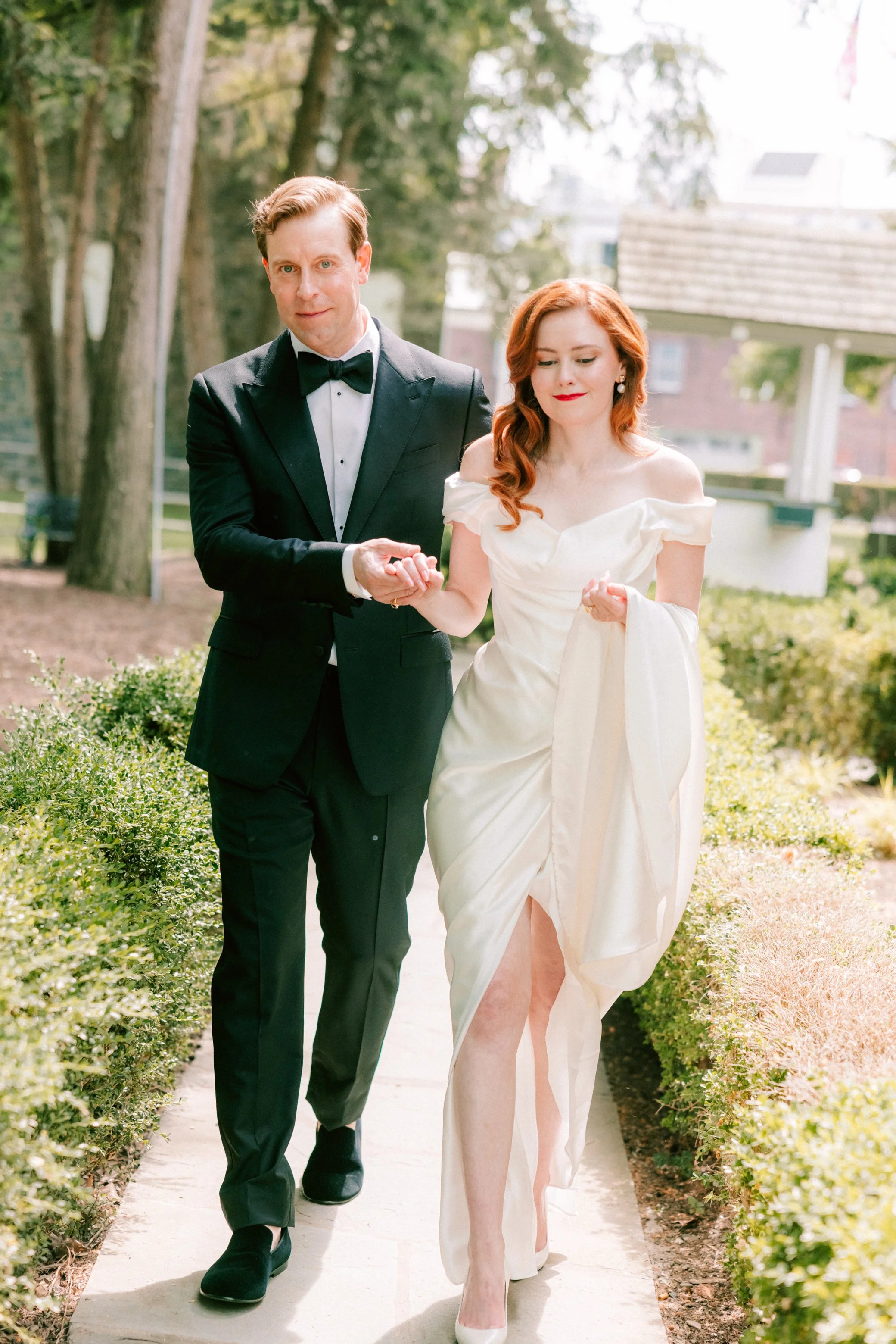 bride and groom holding hands and walking on sidewalk at senate garage