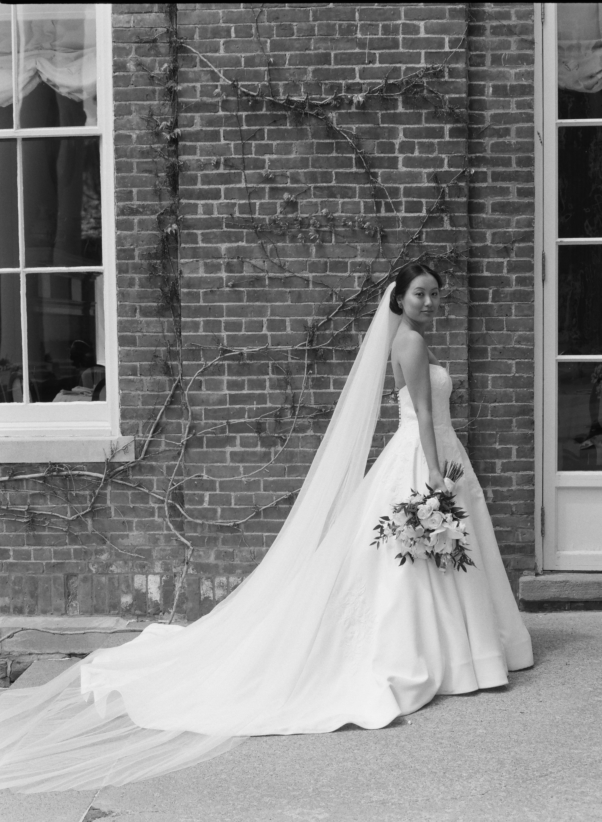 bride standing in front of brick on her wedding day at The Otesaga