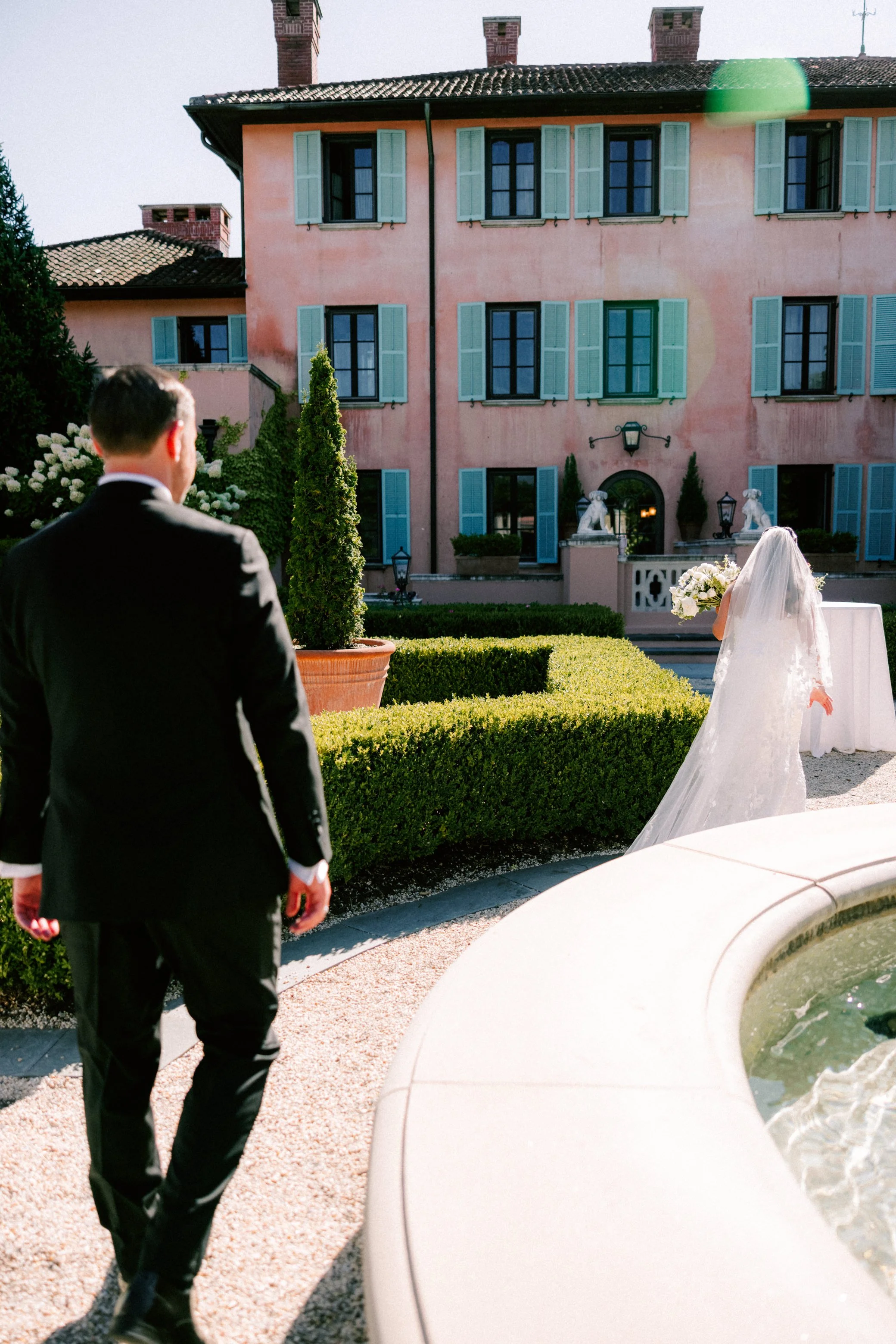 wedding couple walk around the fountain in the gardens at Glenmere Mansion