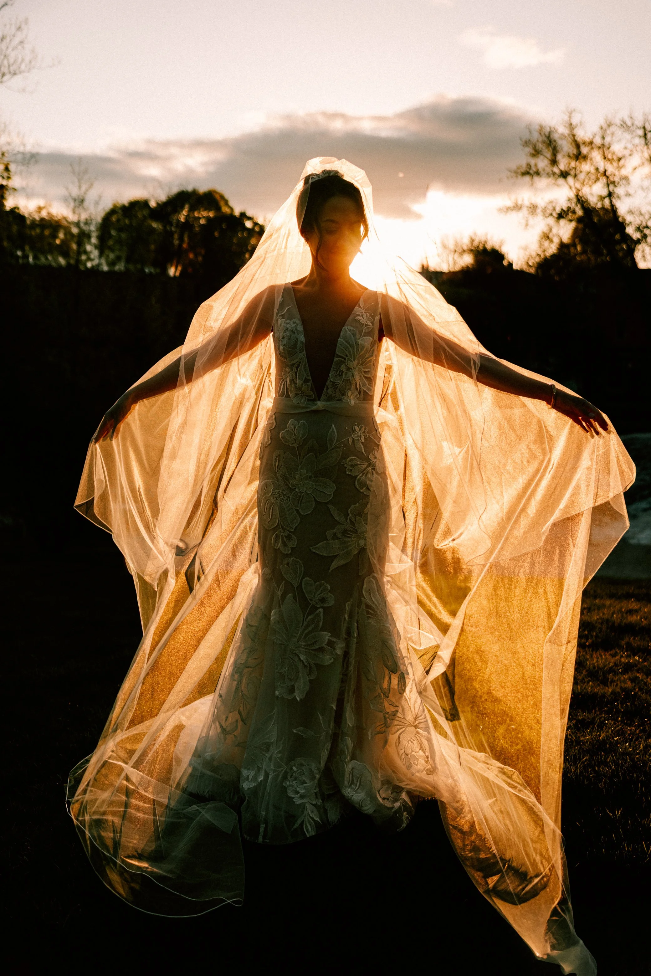bride holds out her veil while the golden hour sunlight illuminates it on her wedding day at the roundhouse in beacon ny