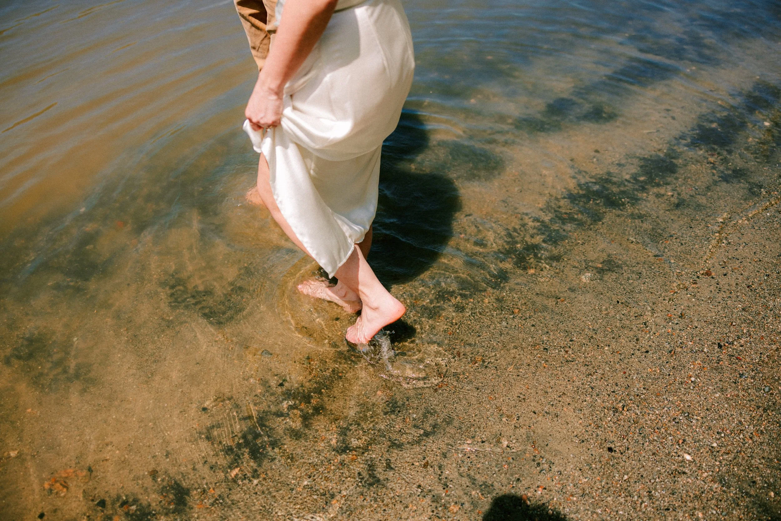 couple walking into the hudson river at little stony point during their engagement photo shoot
