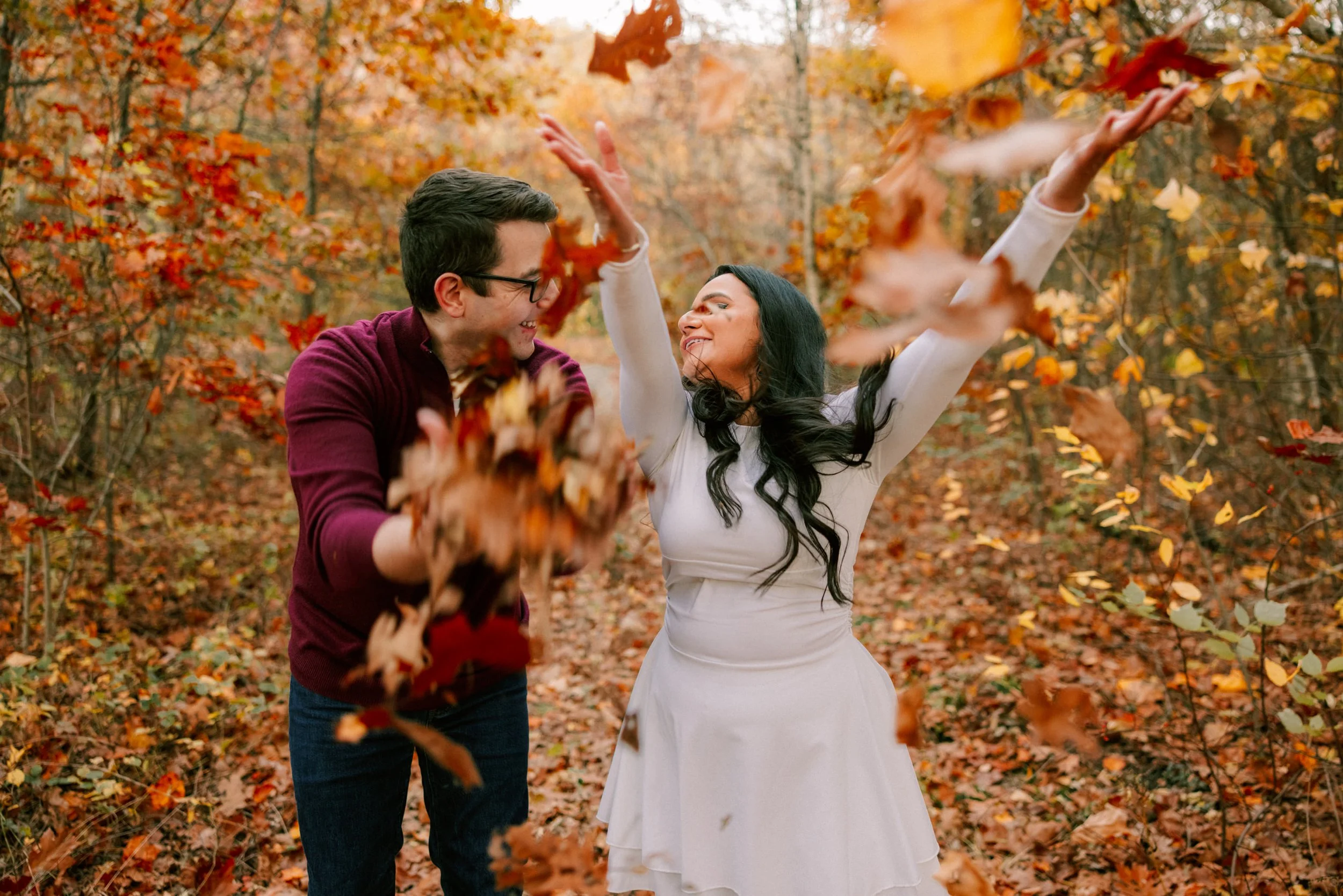 engaged couple throw leaves in the air in the hudson valley during their engagement photo shoot