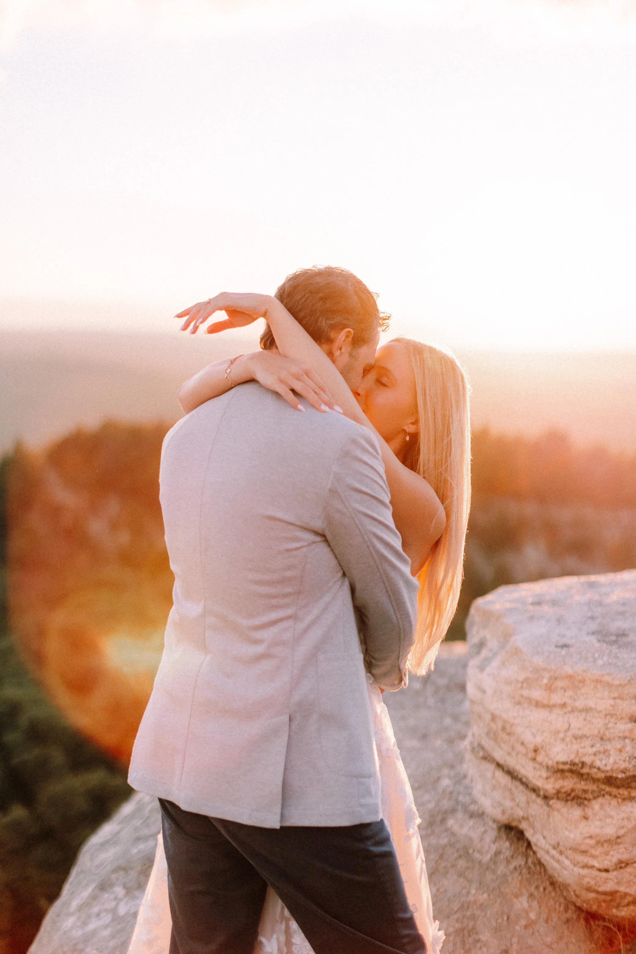 engaged couple embrace at Sky Top during golden hour after their surprise proposal at Mohonk Mountain House
