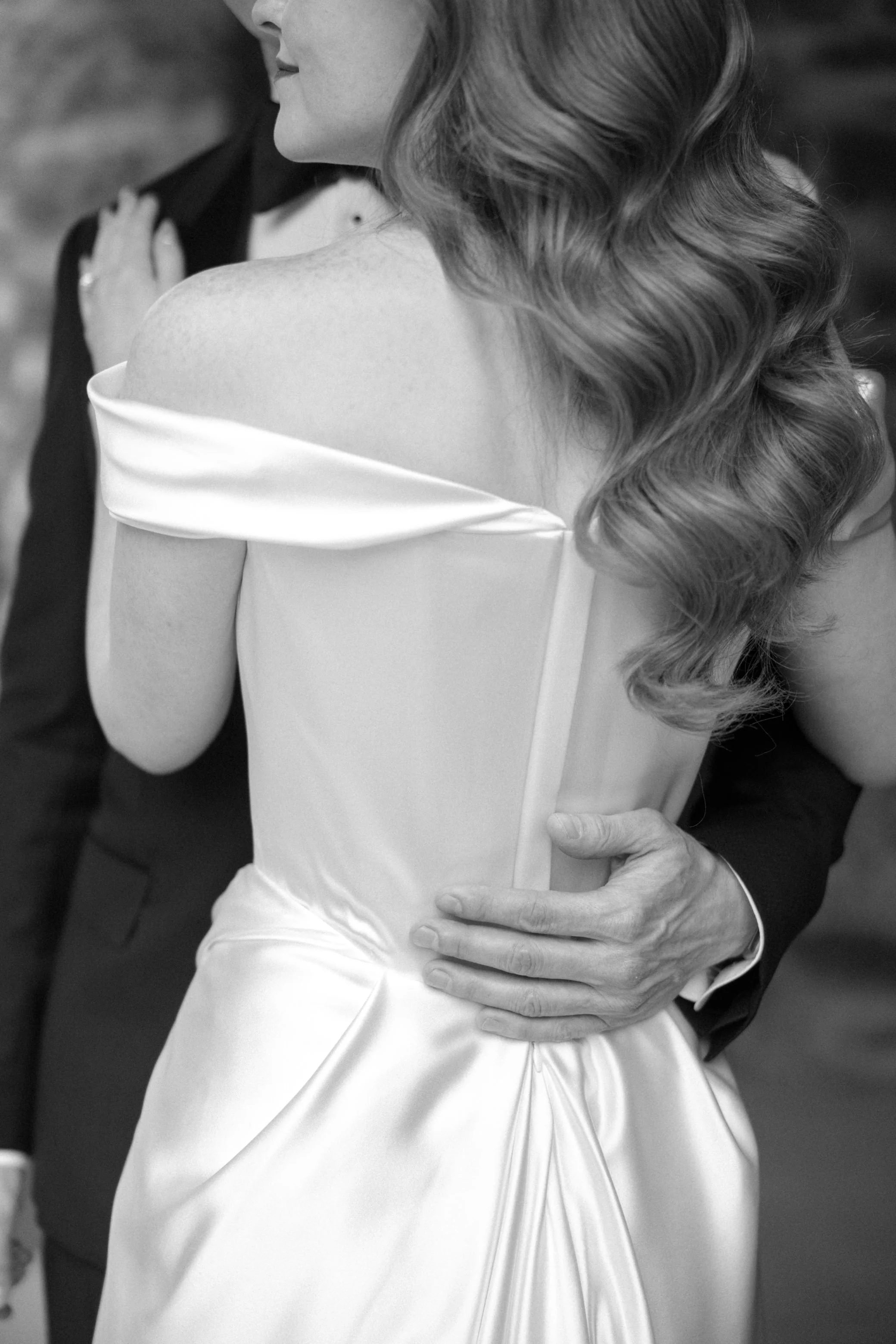 back of bride's vivienne westwood dress with old hollywood waves in her hair with grooms hand on her back