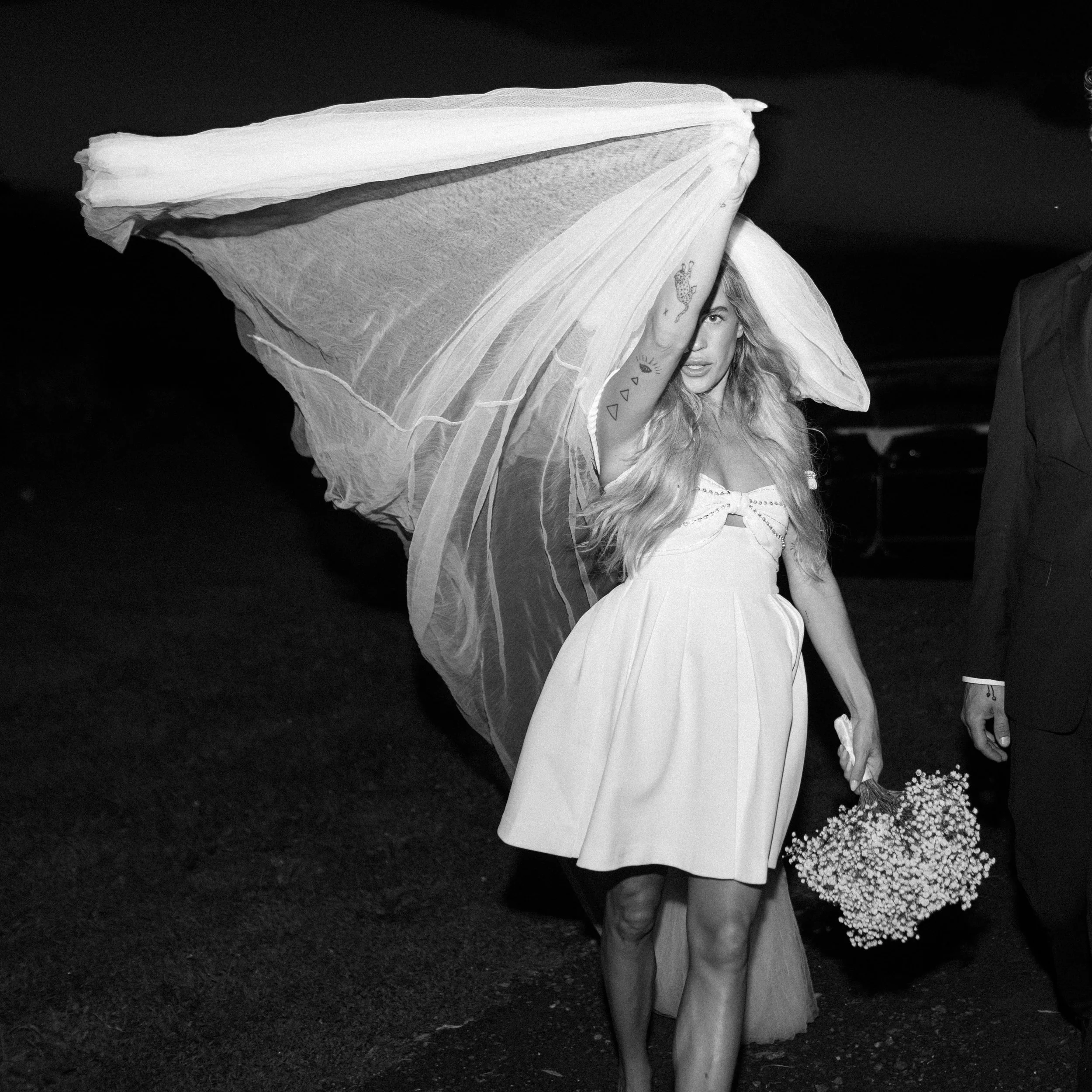 black and white photograph of bride wearing a short wedding dress holding her babys breath bouquet and throwing her veil around on her elopement in the hudson valley