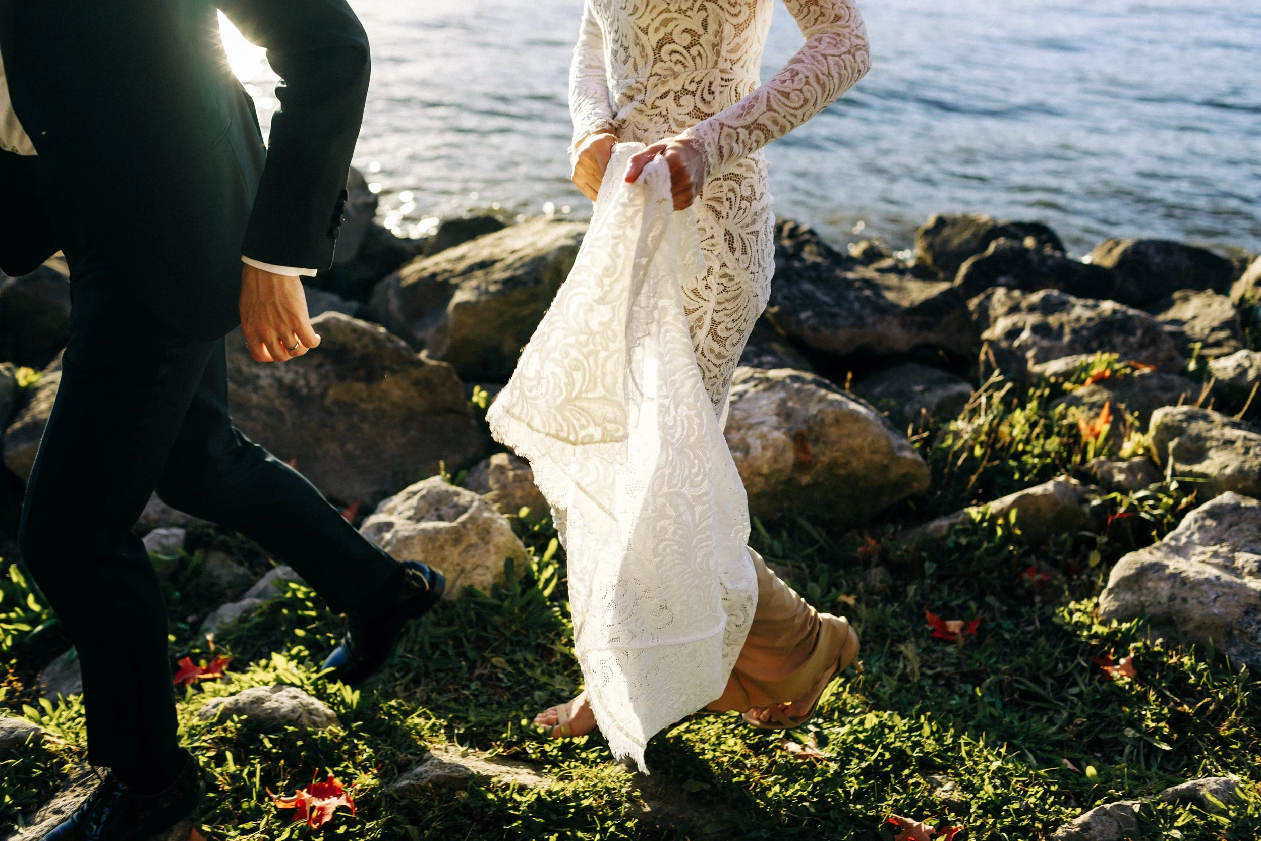 photograph of the legs of a bride and groom walking on the rocky shore of the hudson river during their elopement
