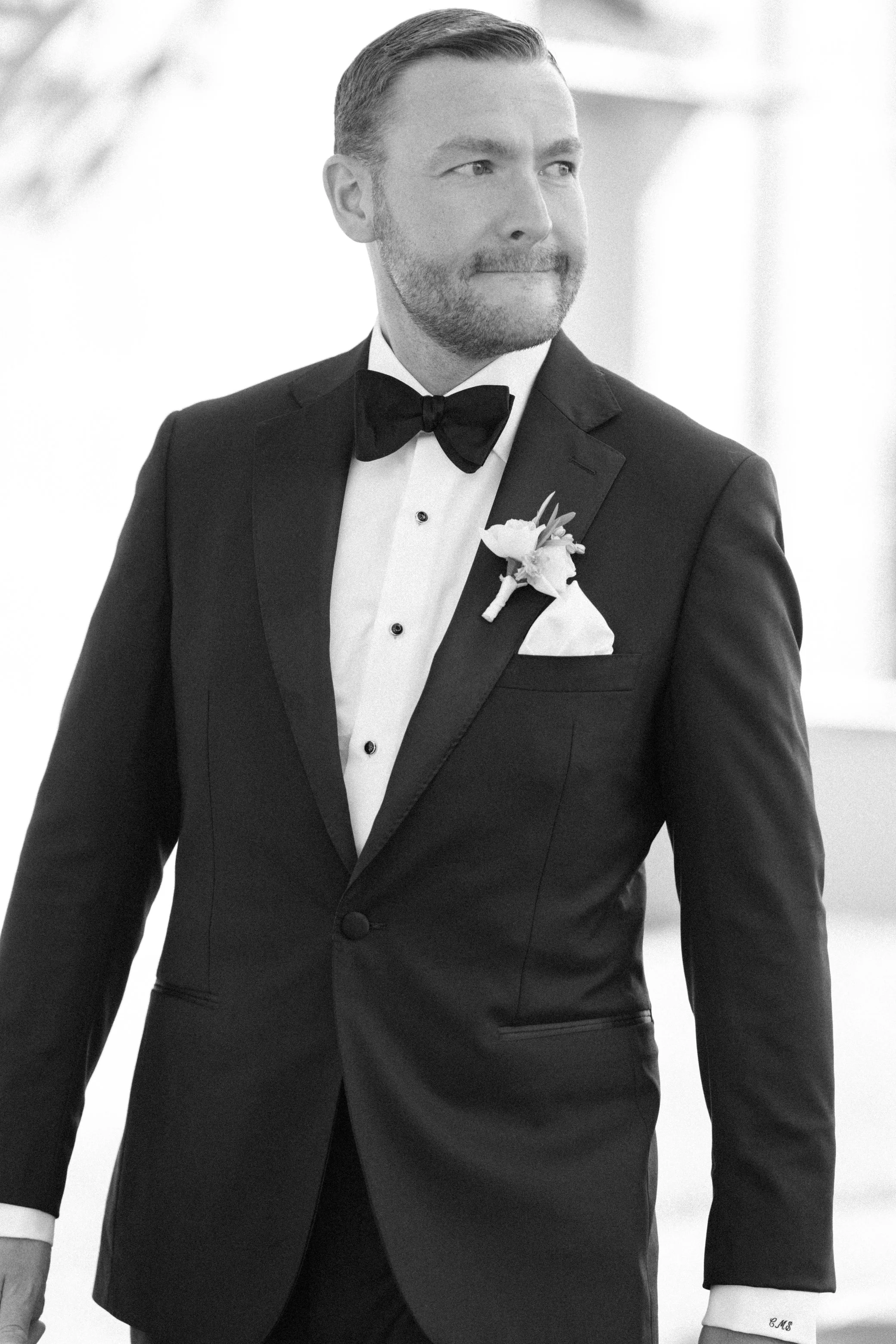 black and white photograph of groom wearing black tux walking on his wedding day at glenmere mansion