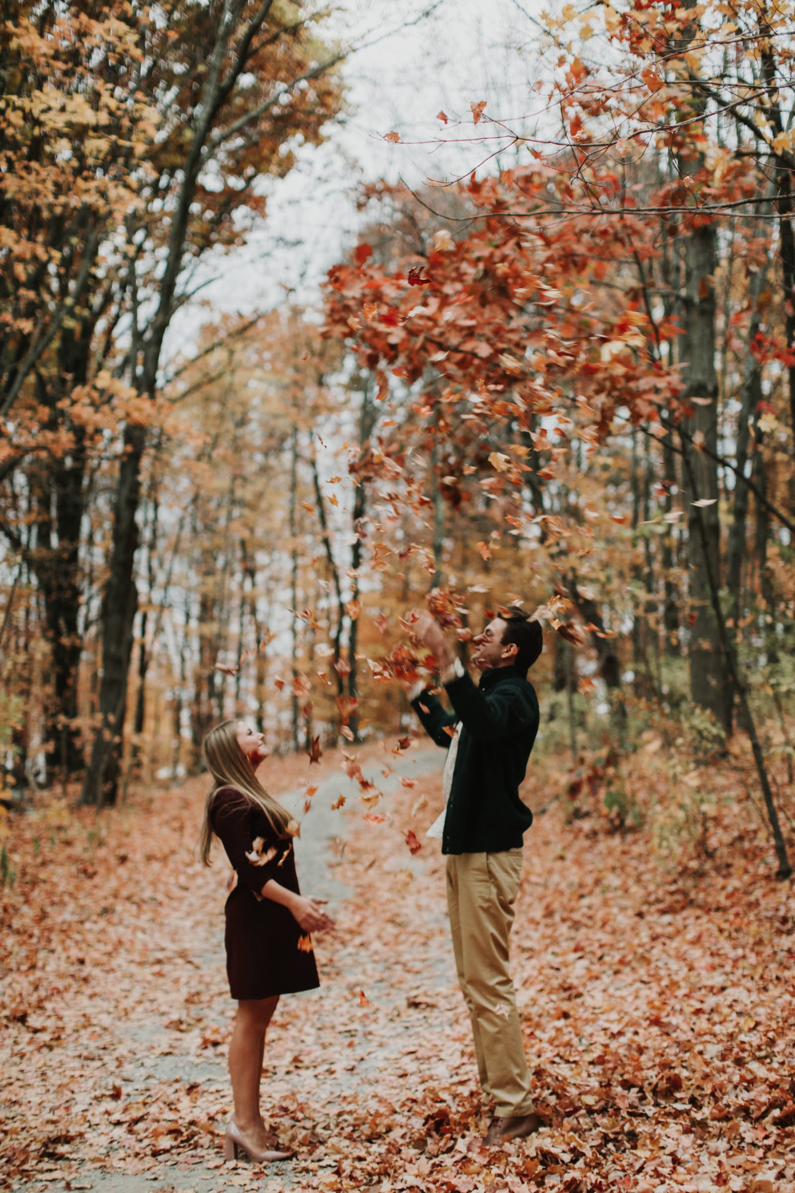 couple throwing leaves in the air during their engagement shoot at Wings Castle in Millbrook, NY