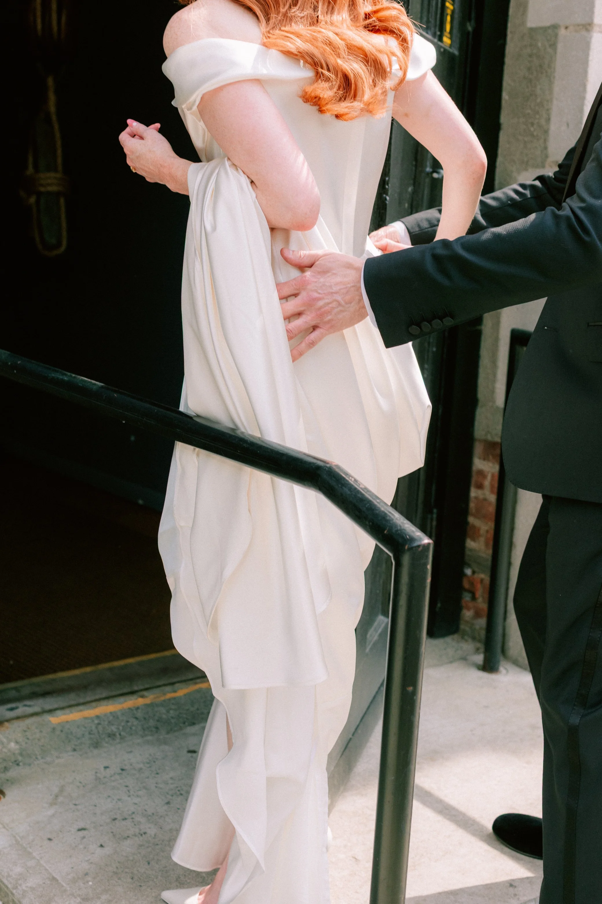 bride walking into a building in vivienne westwood wedding dress while groom holds her waist from behind