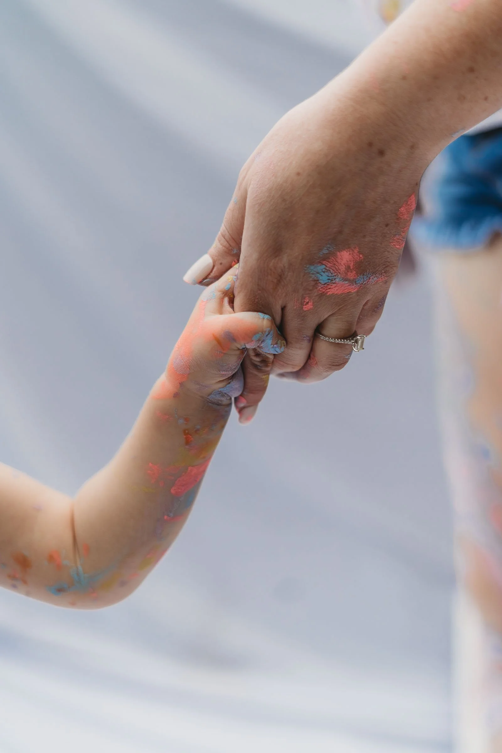 Mom and daughter holding hands covered in paint