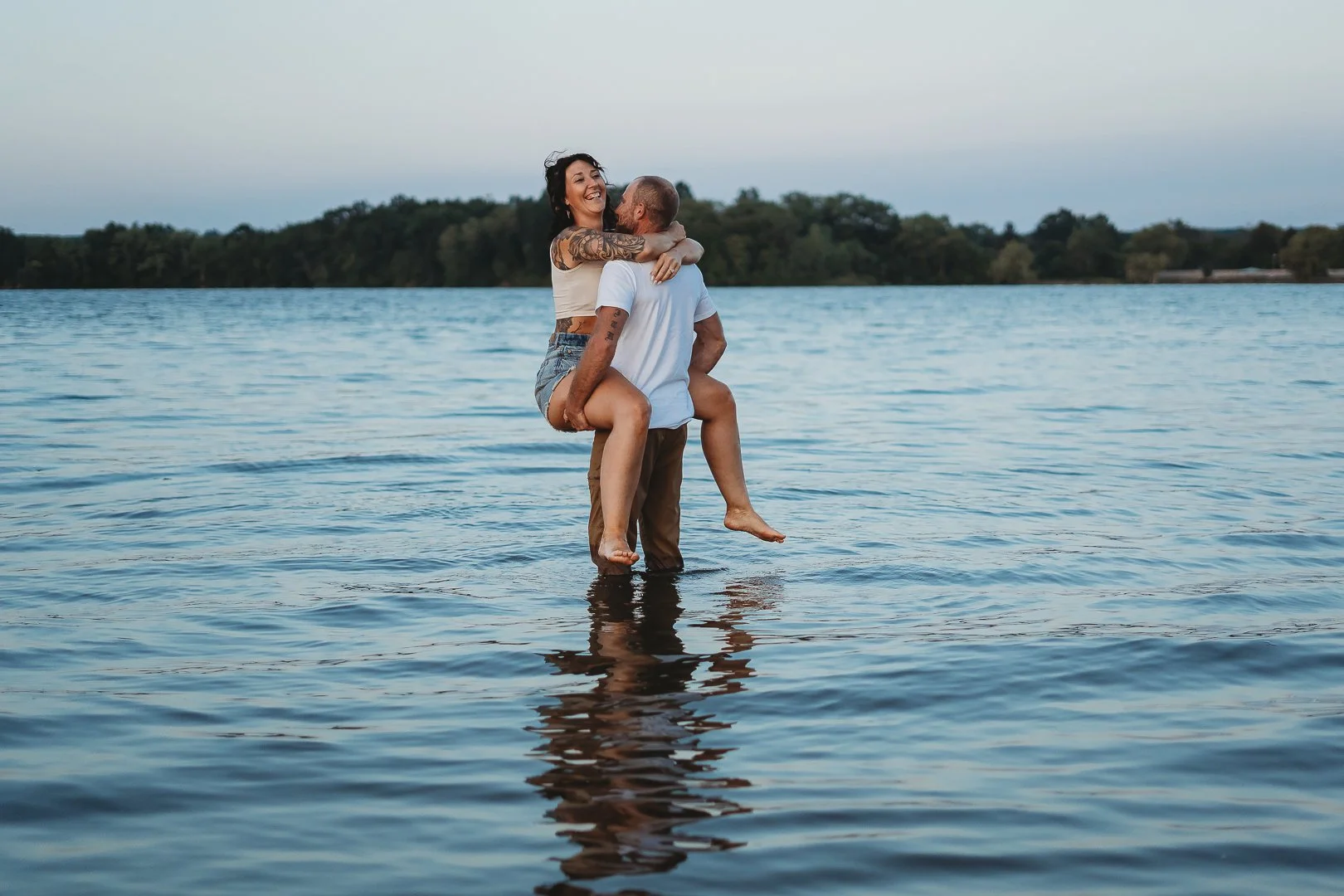 A man carrying a woman in his arms while standing in a lake.