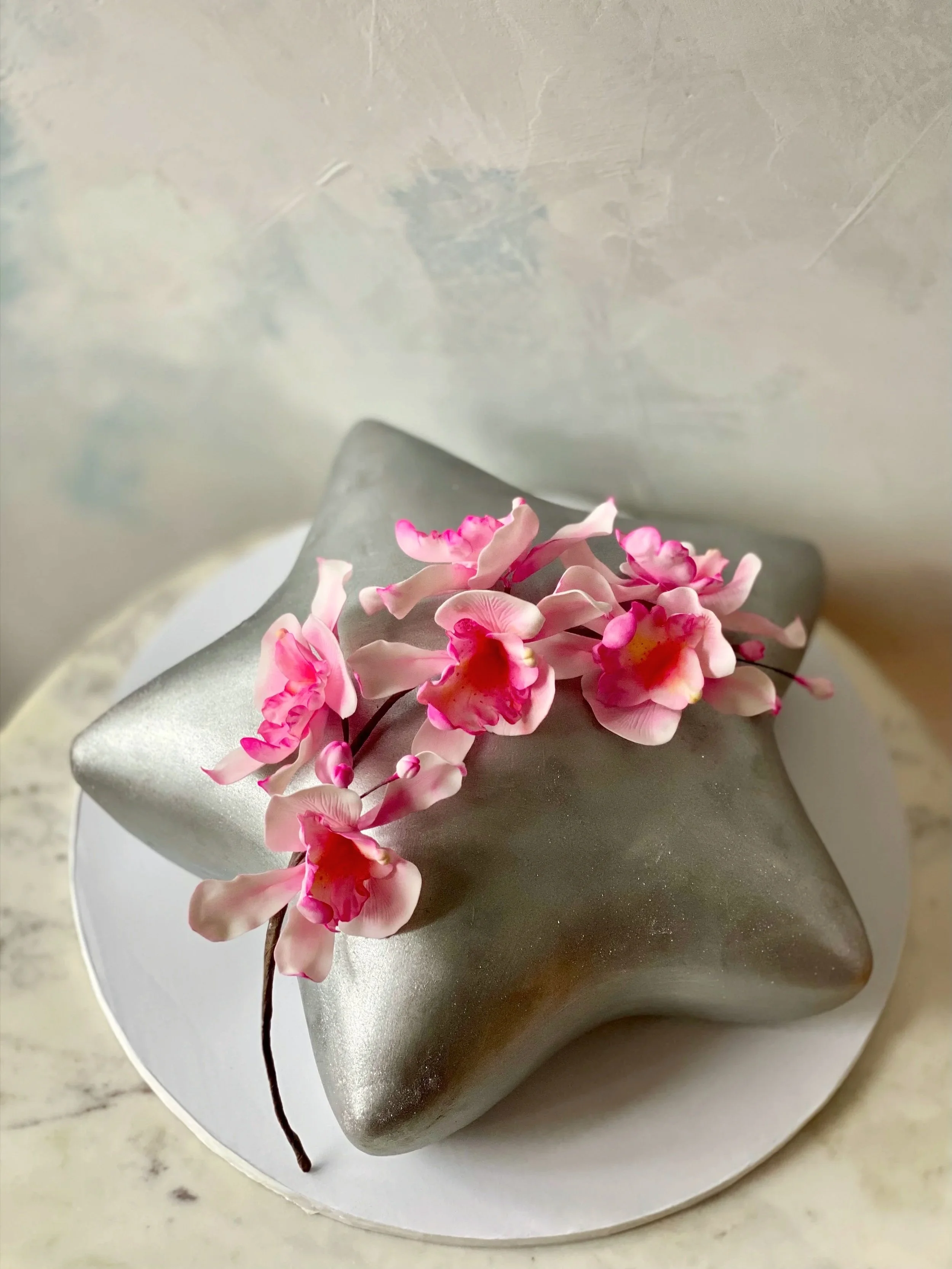 Sculpted silver star gluten-free, organic birthday cake with pink sugar orchids. 