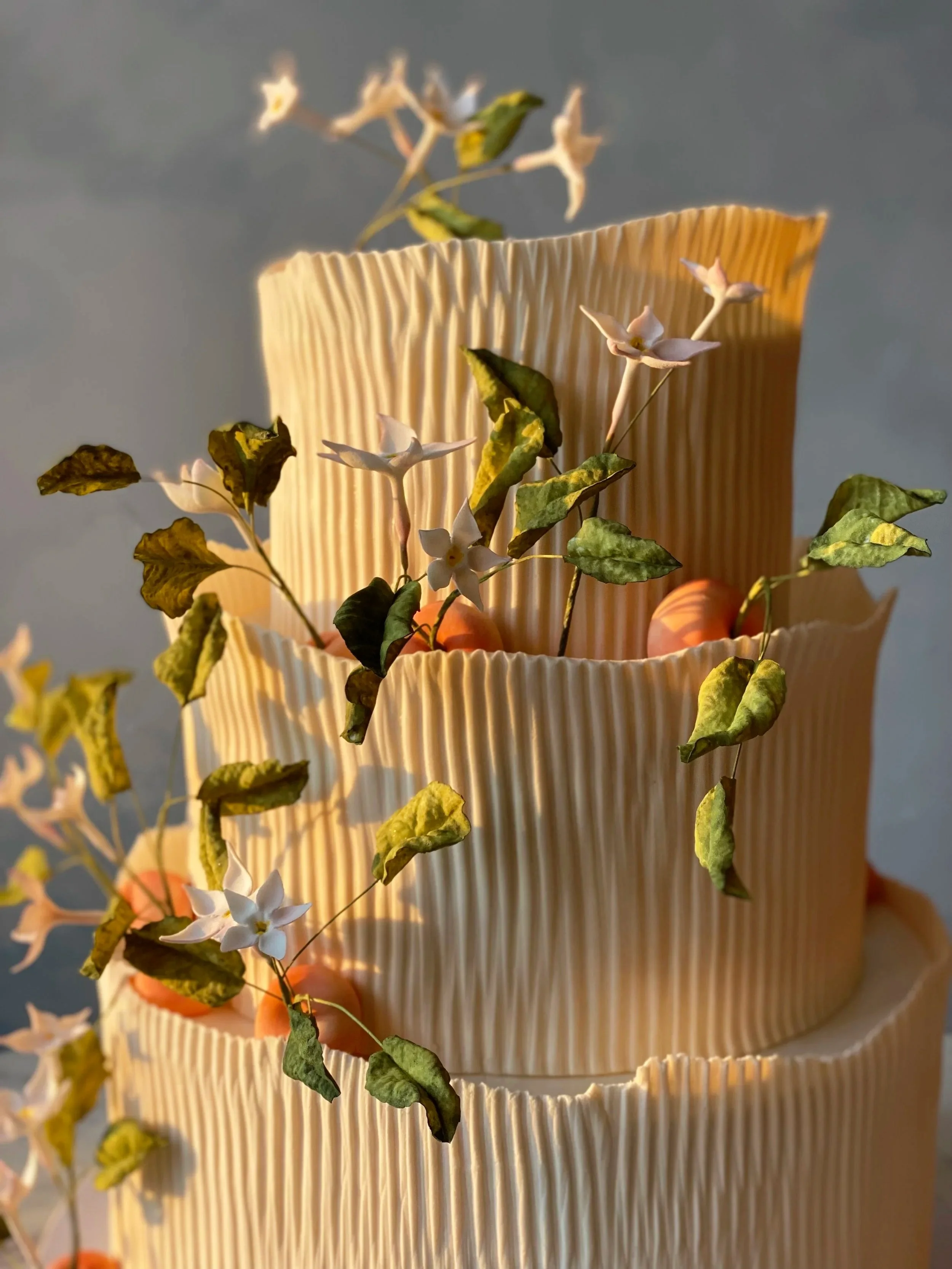 Crepe paper textured fondant with whimsical sculpted peaches and flowers for a wedding in Brooklyn, NYC.