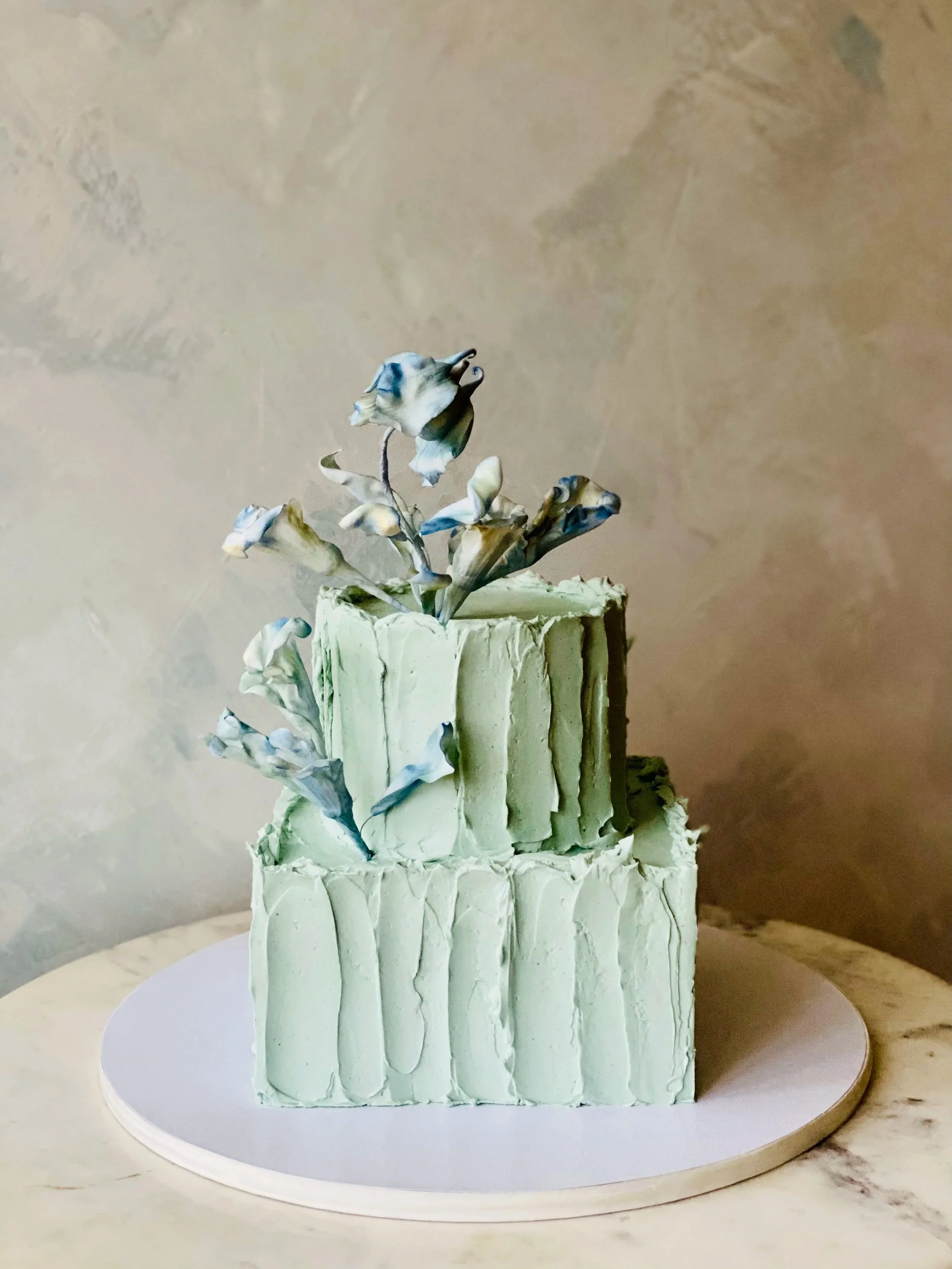 Blue meringue textured icing on a sweetheart slicing wedding cake with unique artistic decor. 
