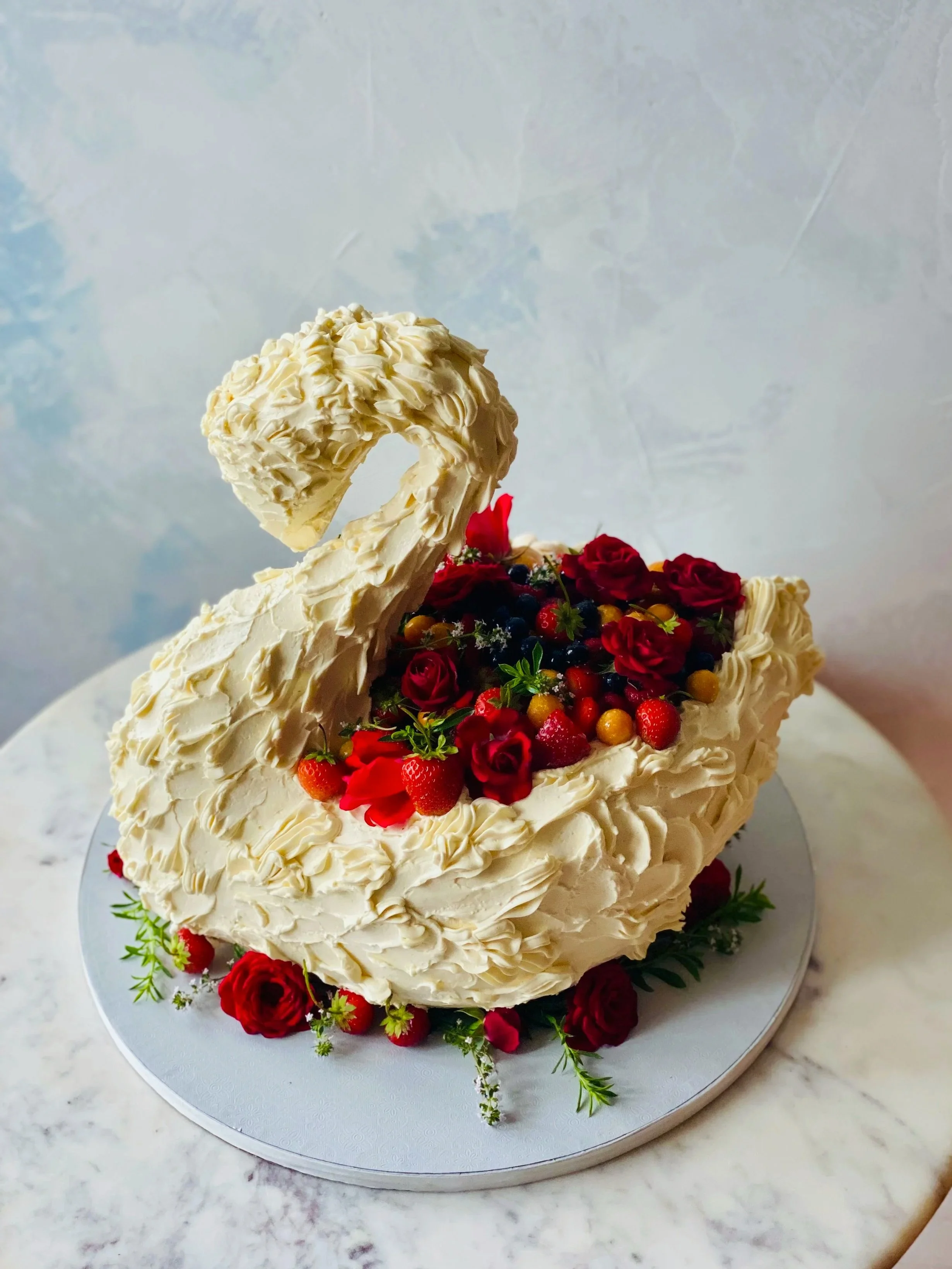 Sculpted organic swan cake with messy romanic icing, edible flowers, berries and herbs.