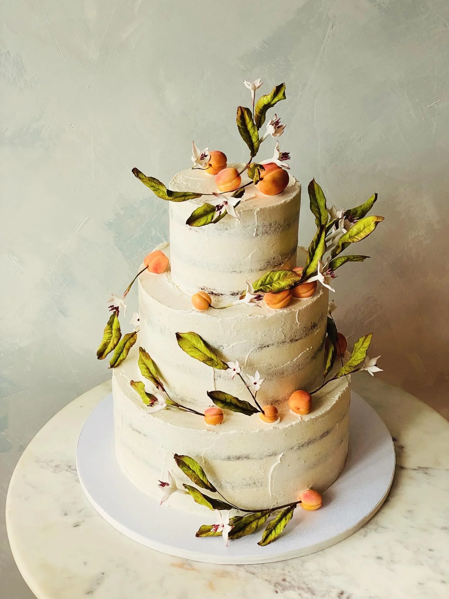 Semi-naked spackled buttercream with peach blossom branches for a gluten-free, organic wedding cake that's minimal, elegant and artistic. 