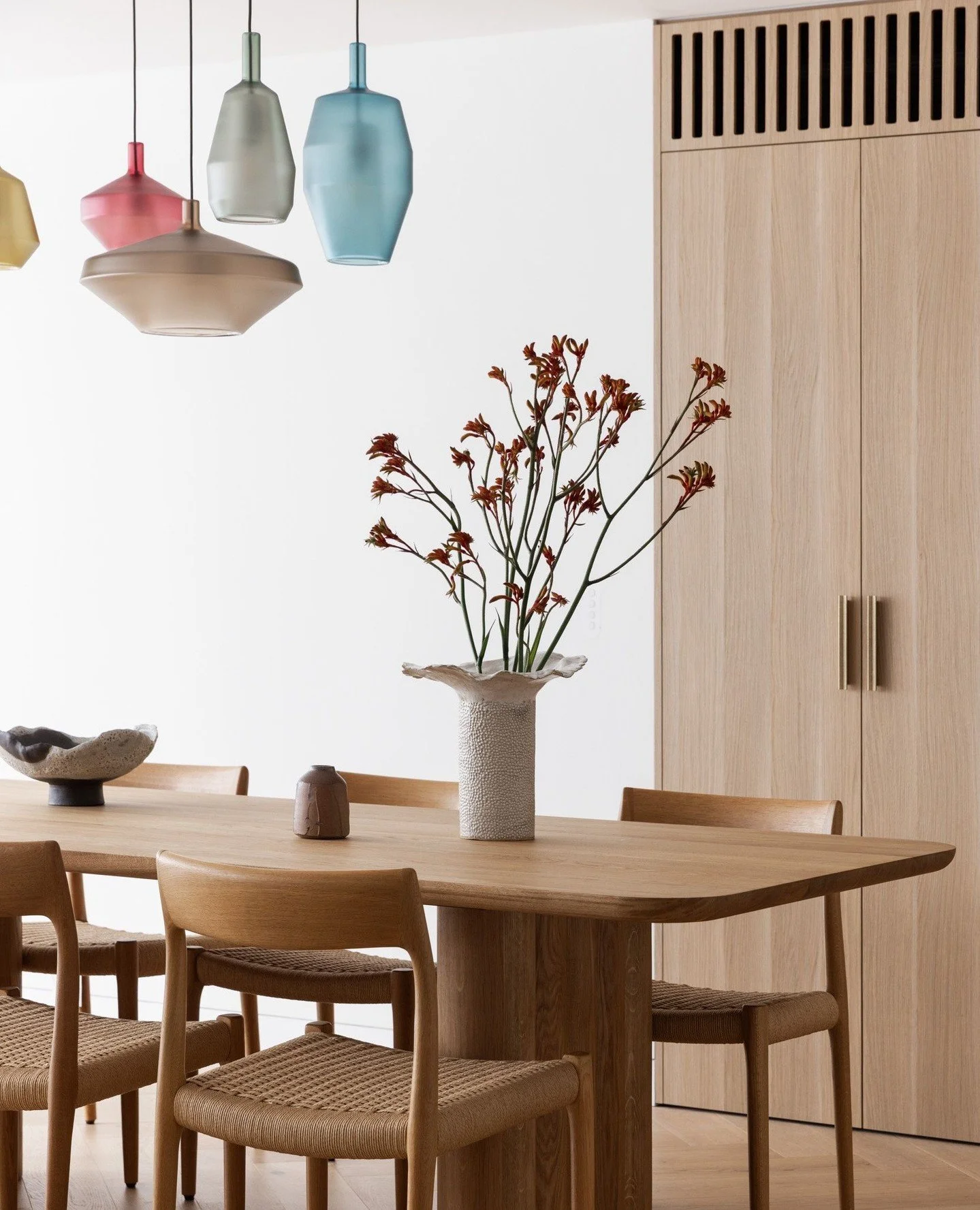 In this compact dining and living space, simplicity does the heavy lifting. A restrained palette keeps the apartment feeling calm and cohesive, while jewel-like splashes of colour bring just the right amount of personality.⁠
⁠
Glass pendants above th