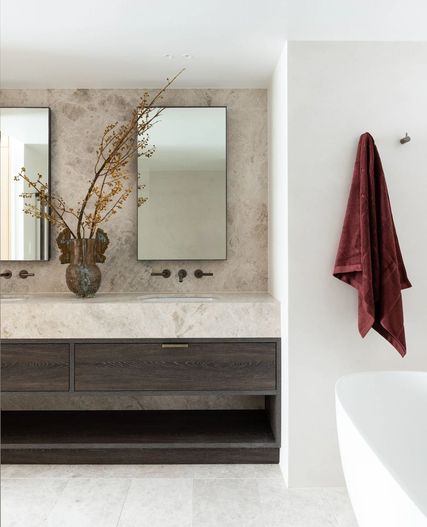 A primary ensuite designed to feel like a private hotel retreat &mdash; calm, cocooning and unapologetically luxurious.⁠
⁠
Natural stone sets the tone, paired with soft microcement walls and anchored by dark timber veneer joinery. The palette is rest